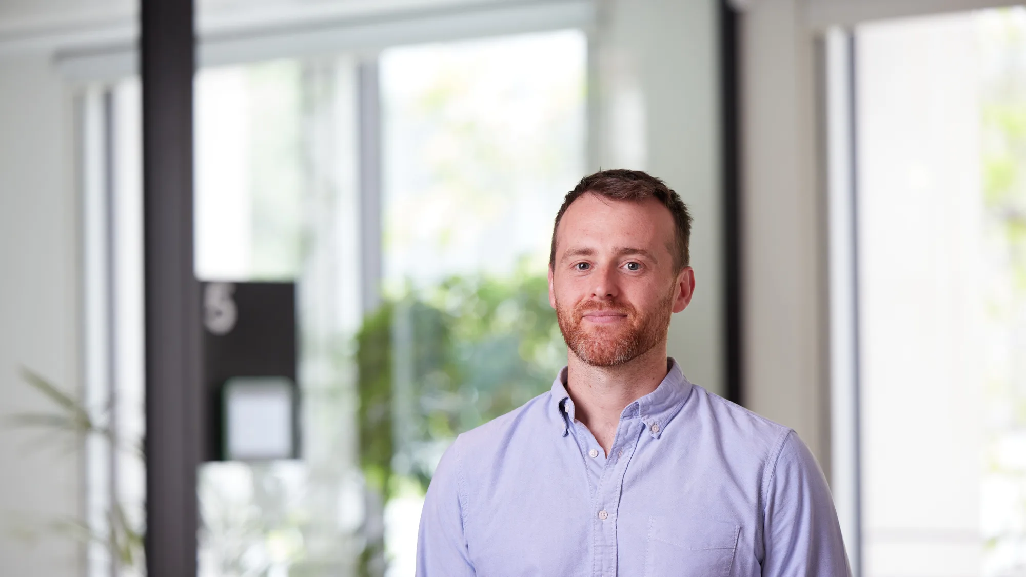 Andrew Livesey looking towards the camera wearing a light blue shirt