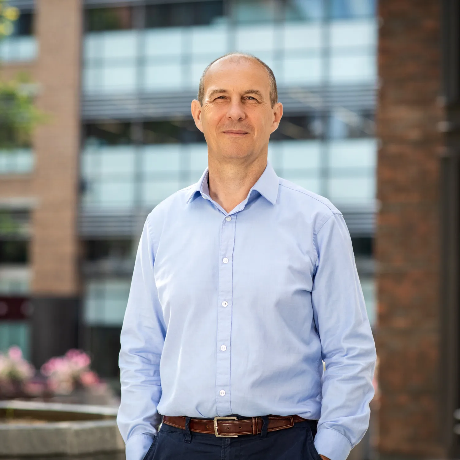 Andrew Moore in front of building with trees and plants in background