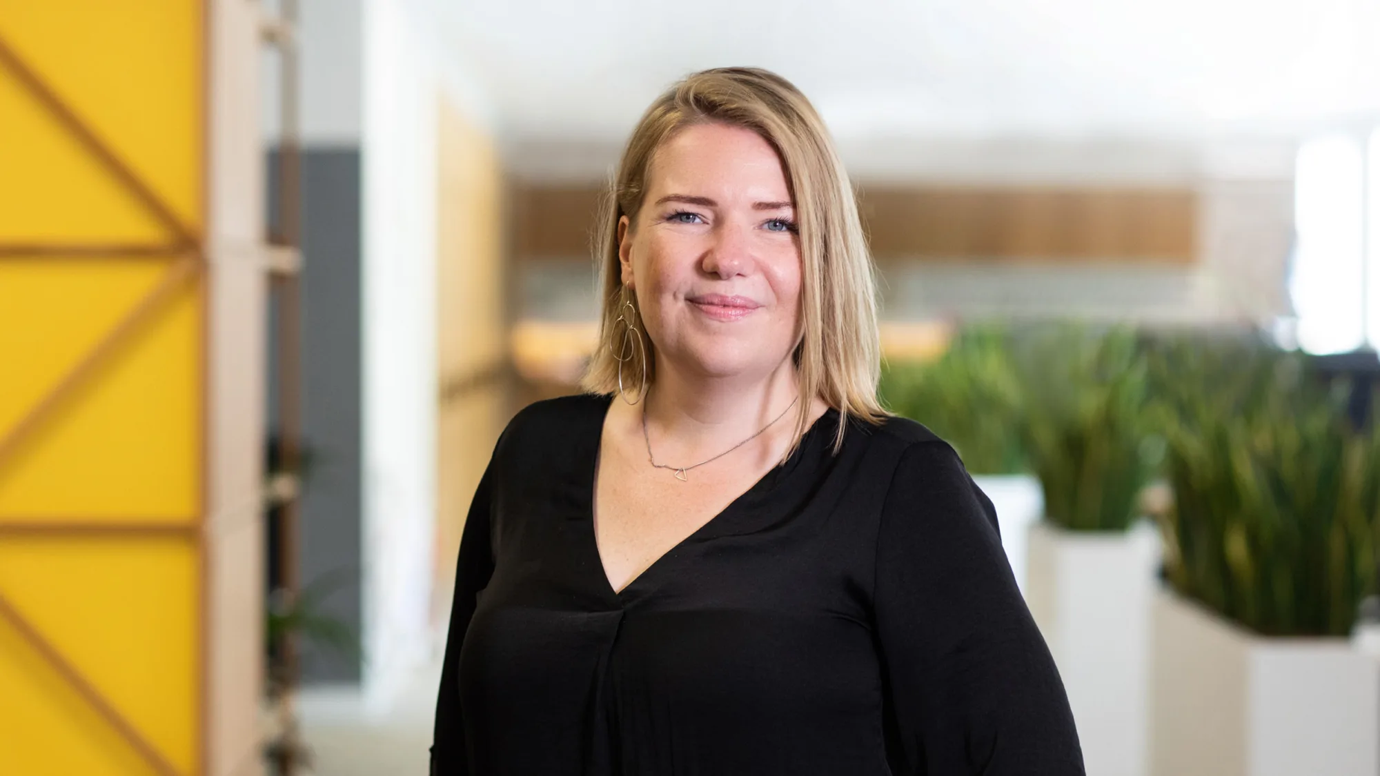 Barbara Sacha in office with plants and yellow storage in background