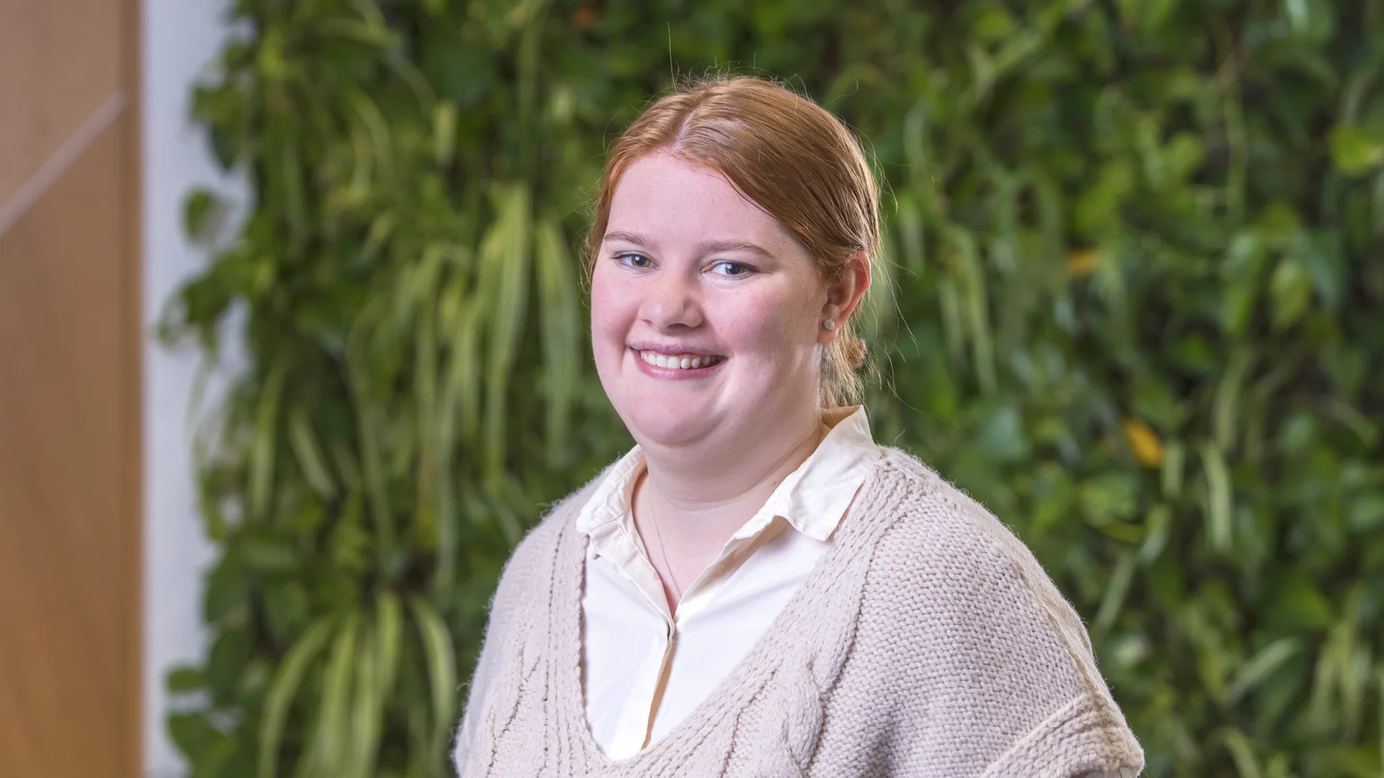 Head and sholders shot of Heater wearing a cream jumper against a background of foliage