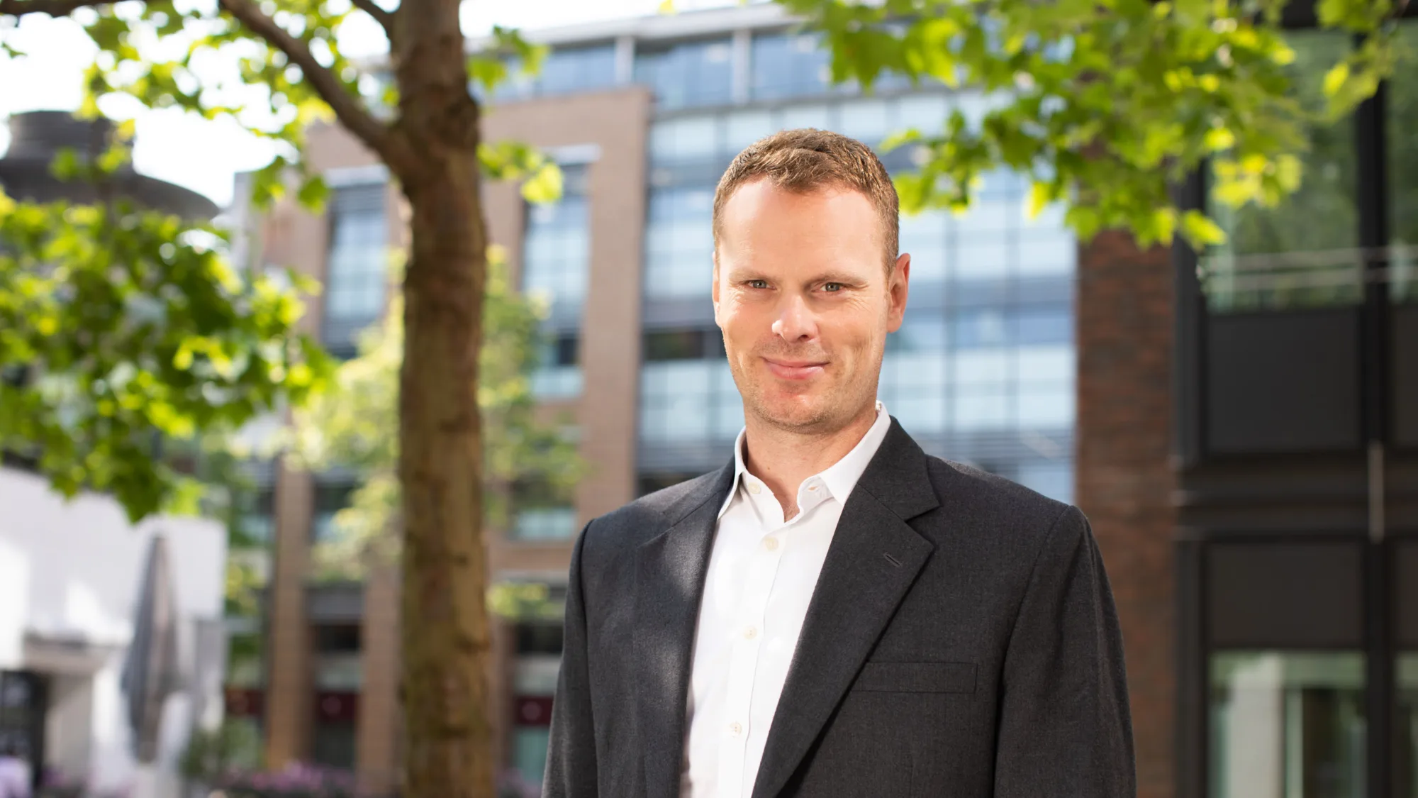 Jonnie Allen underneath a tree with buildings in the background