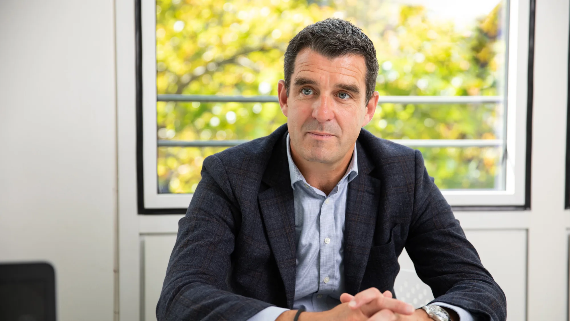 Kevin Hayes in meeting with window behind with trees in