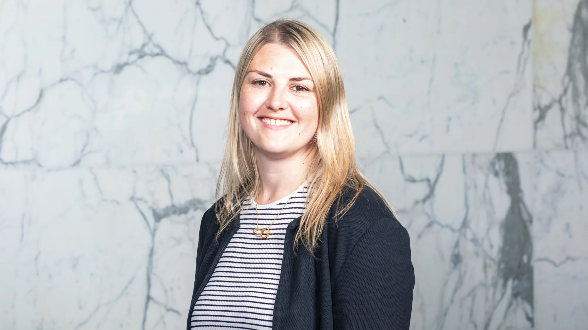 Lucia standing against a marble wall