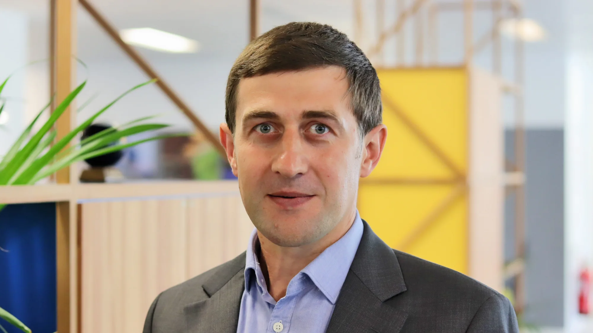 Oleksandr in an open collar shirt and suit jacket in the office space