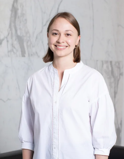 Sarah Linnell standing in front of marble background in a white shirt