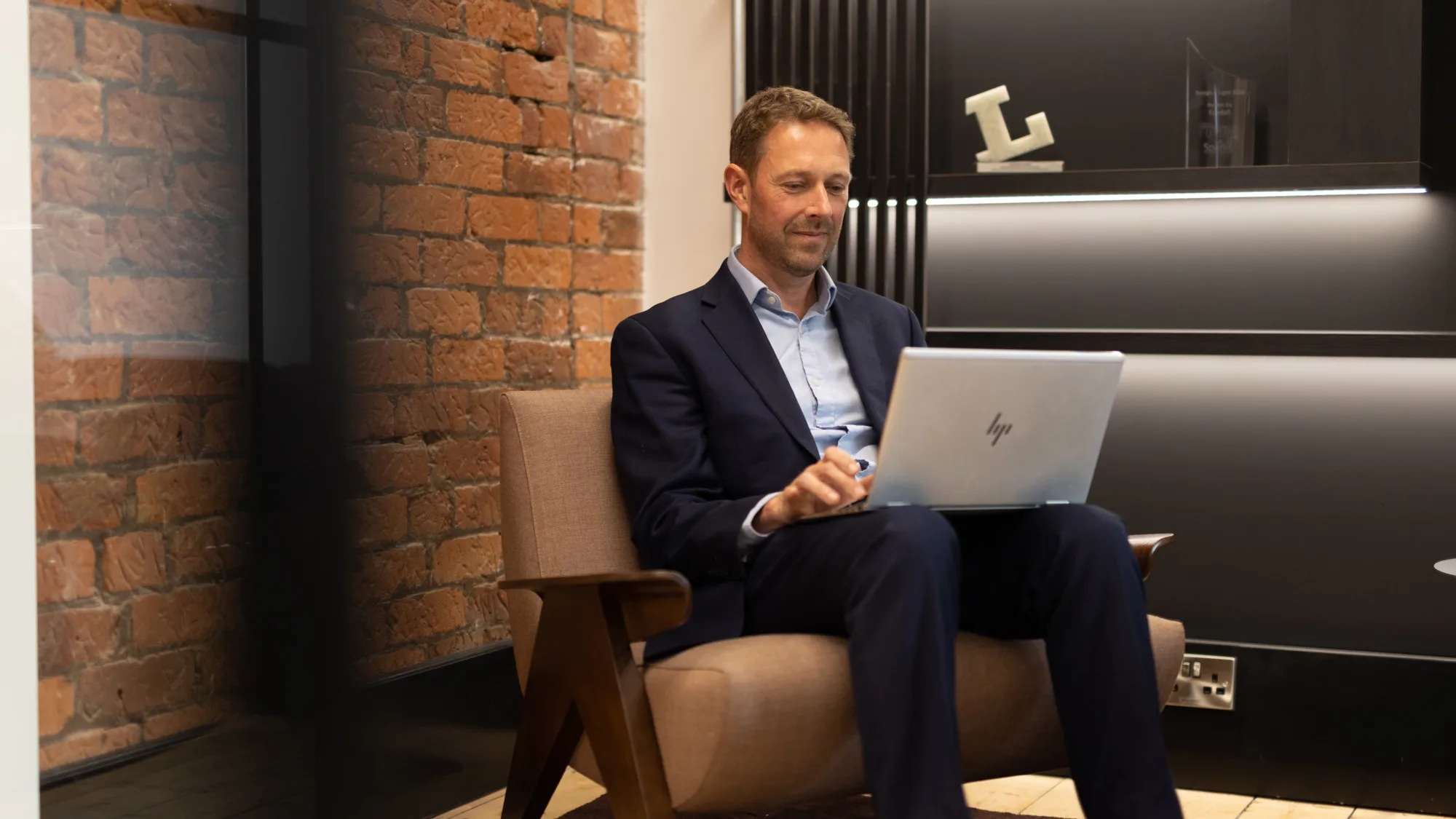 Lee Leston Jones at hot desk in office sitting with a laptop on his legs