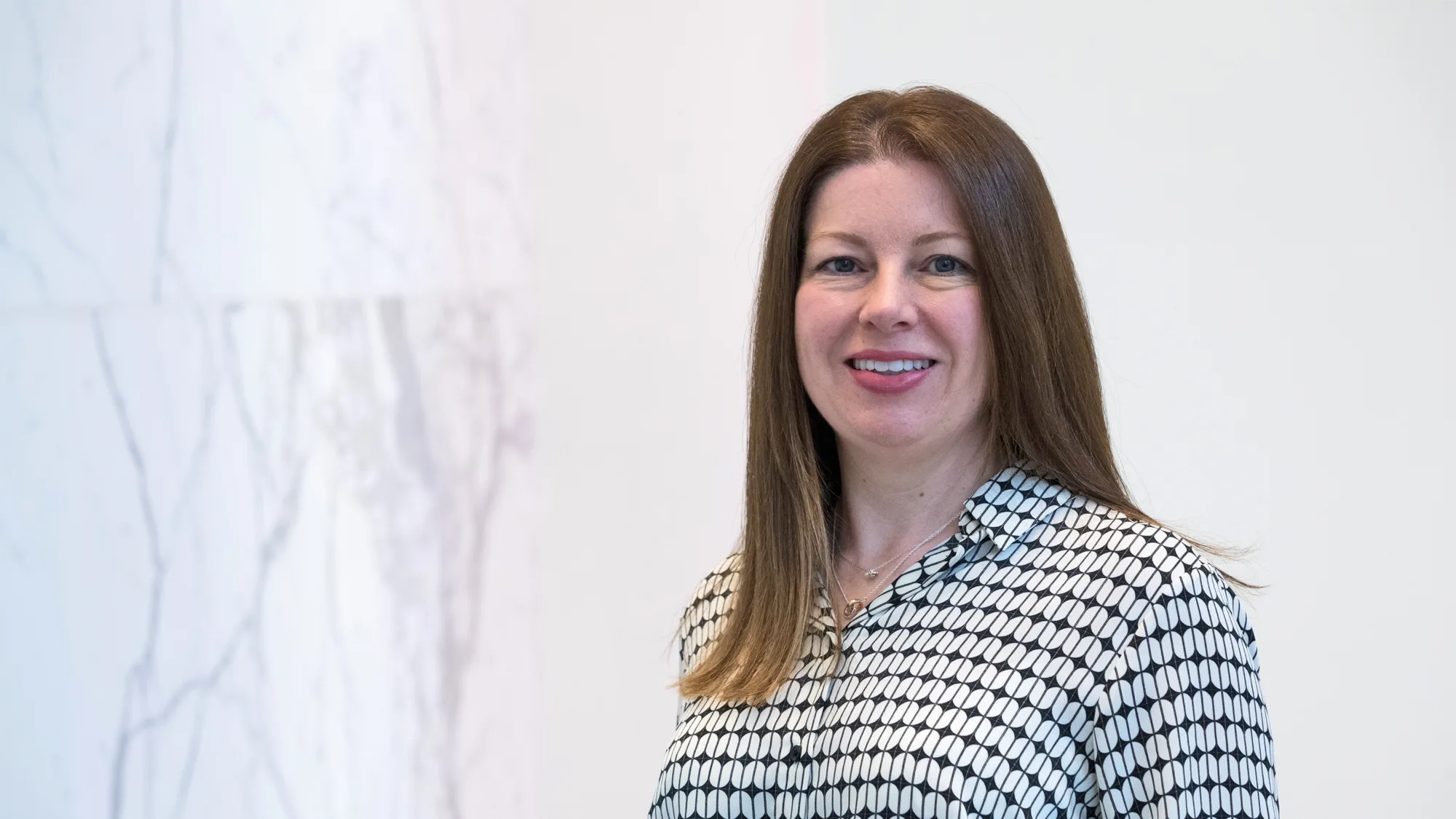 Head and sholders shot of Fiona against a white marbled background wearing a black and white blouse