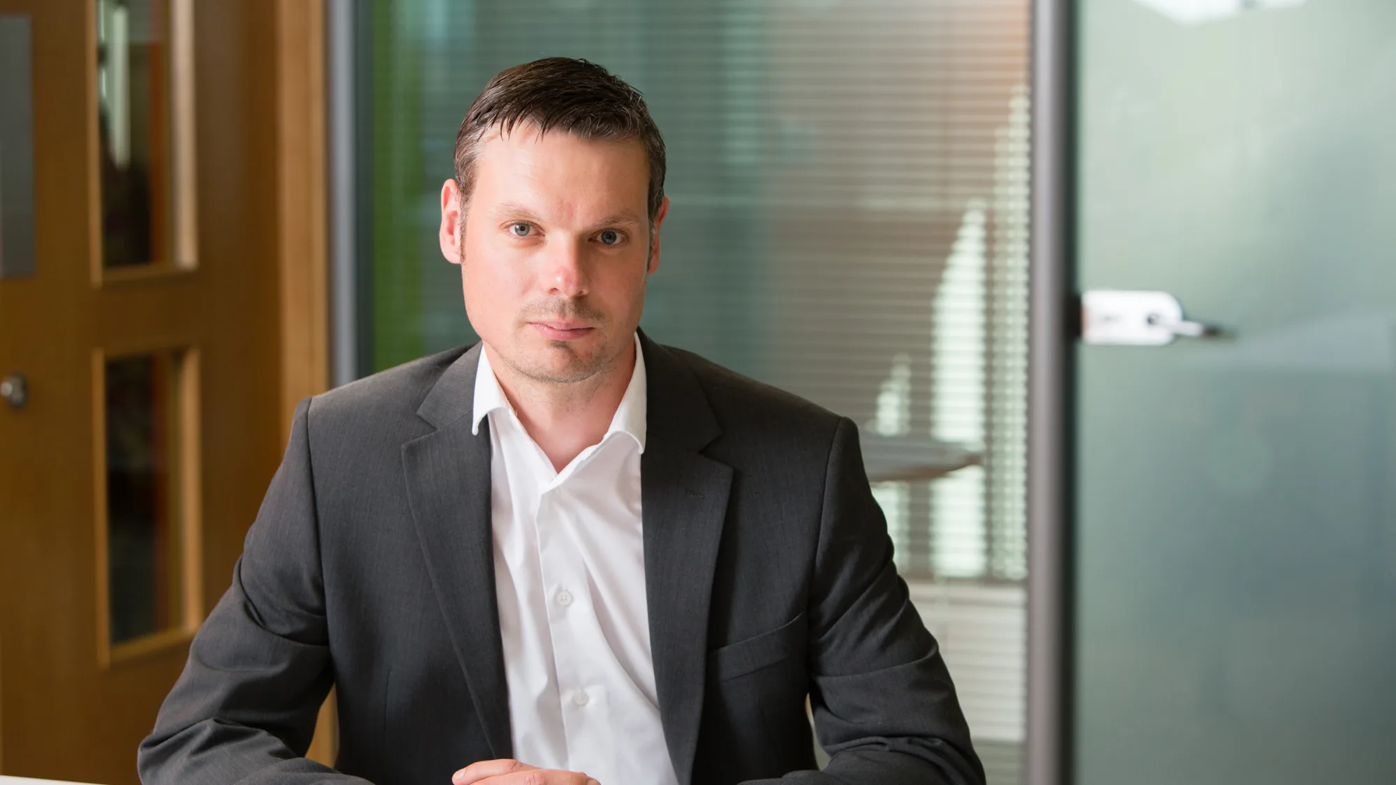 Kevin sat at a desk with his hands interlinked