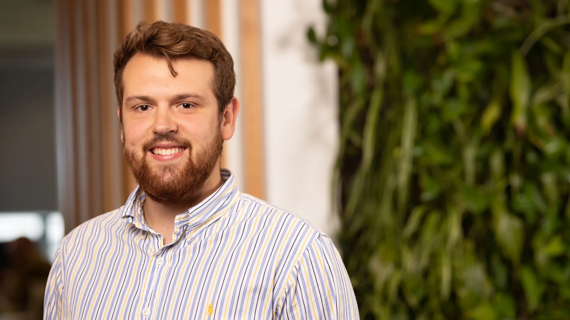 Headshot of Marko, in front of a timber and plant wall.