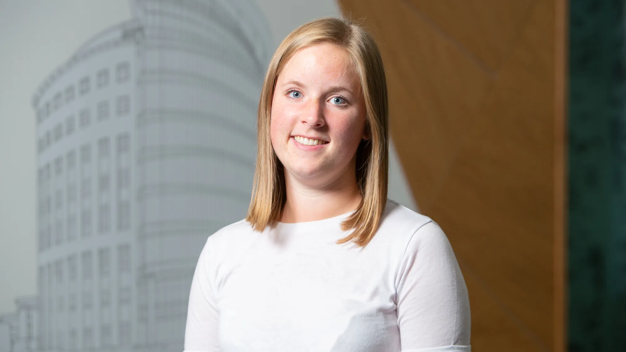 Natalie wearing a short sleeve white t-shirt smiling to camera