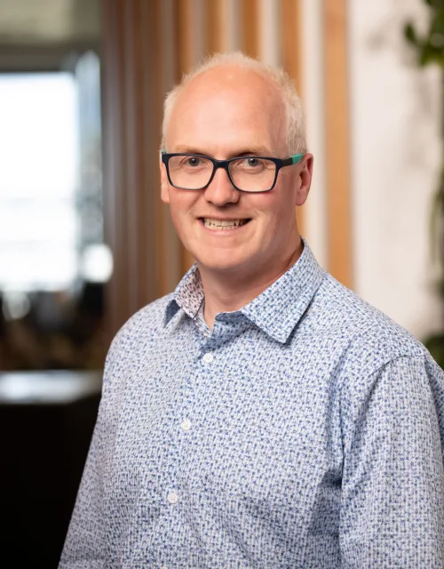Tomas Neeson in office reception with wooden panelling and green wall background