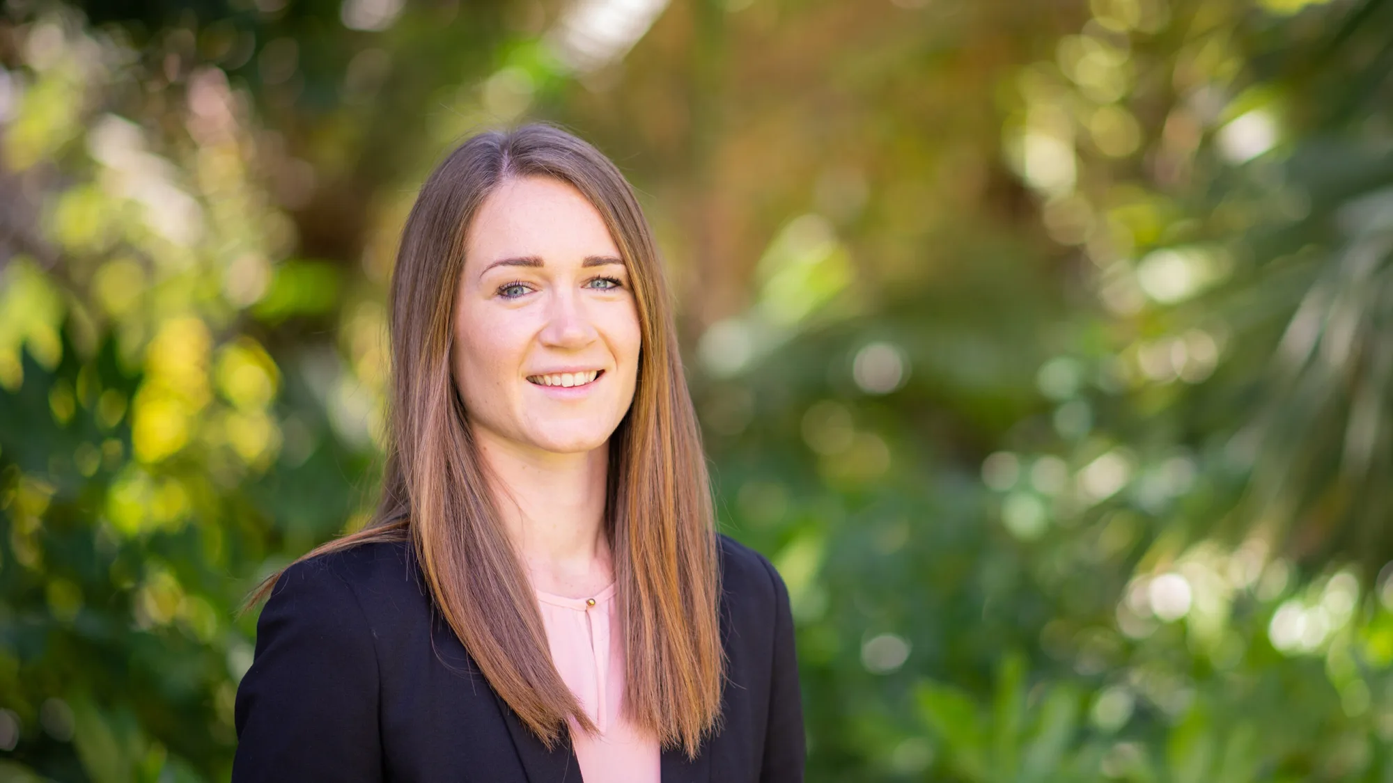 Headshot of Katarina outdoors, in front of greenery.
