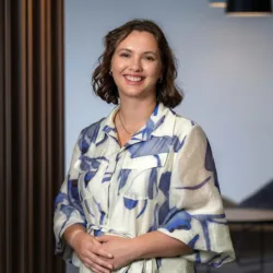 Joanne Sim in a white and blue dress with the office reception area and chair in the background