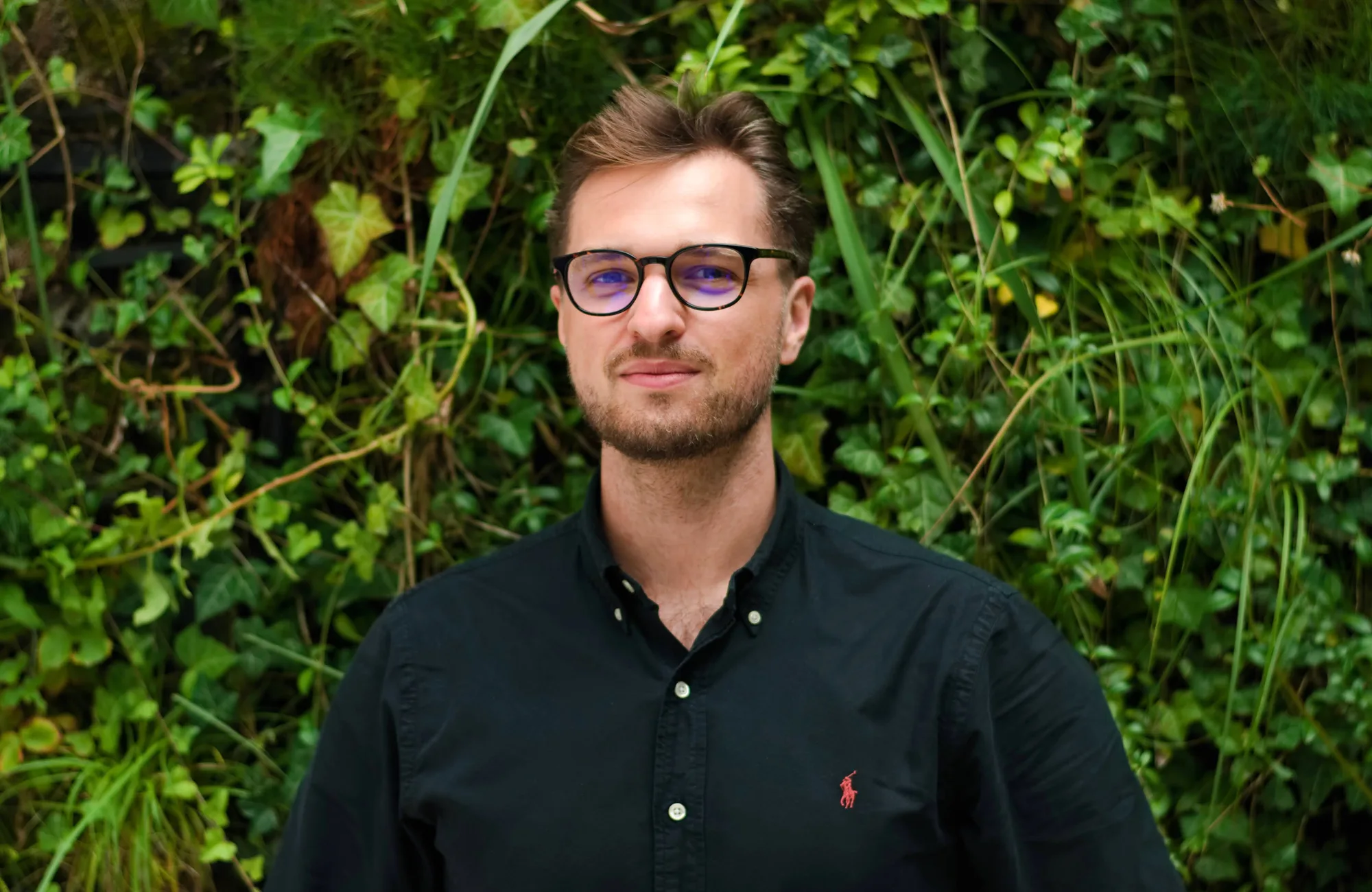 Igor in a dark open collar shirt in front of a living wall