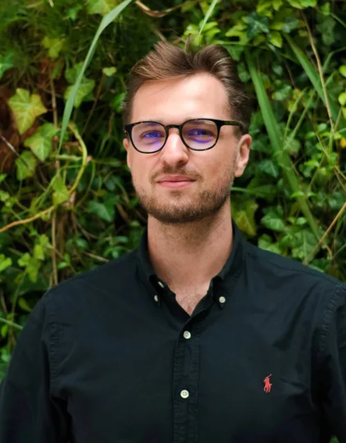 Igor in a dark open collar shirt in front of a living wall