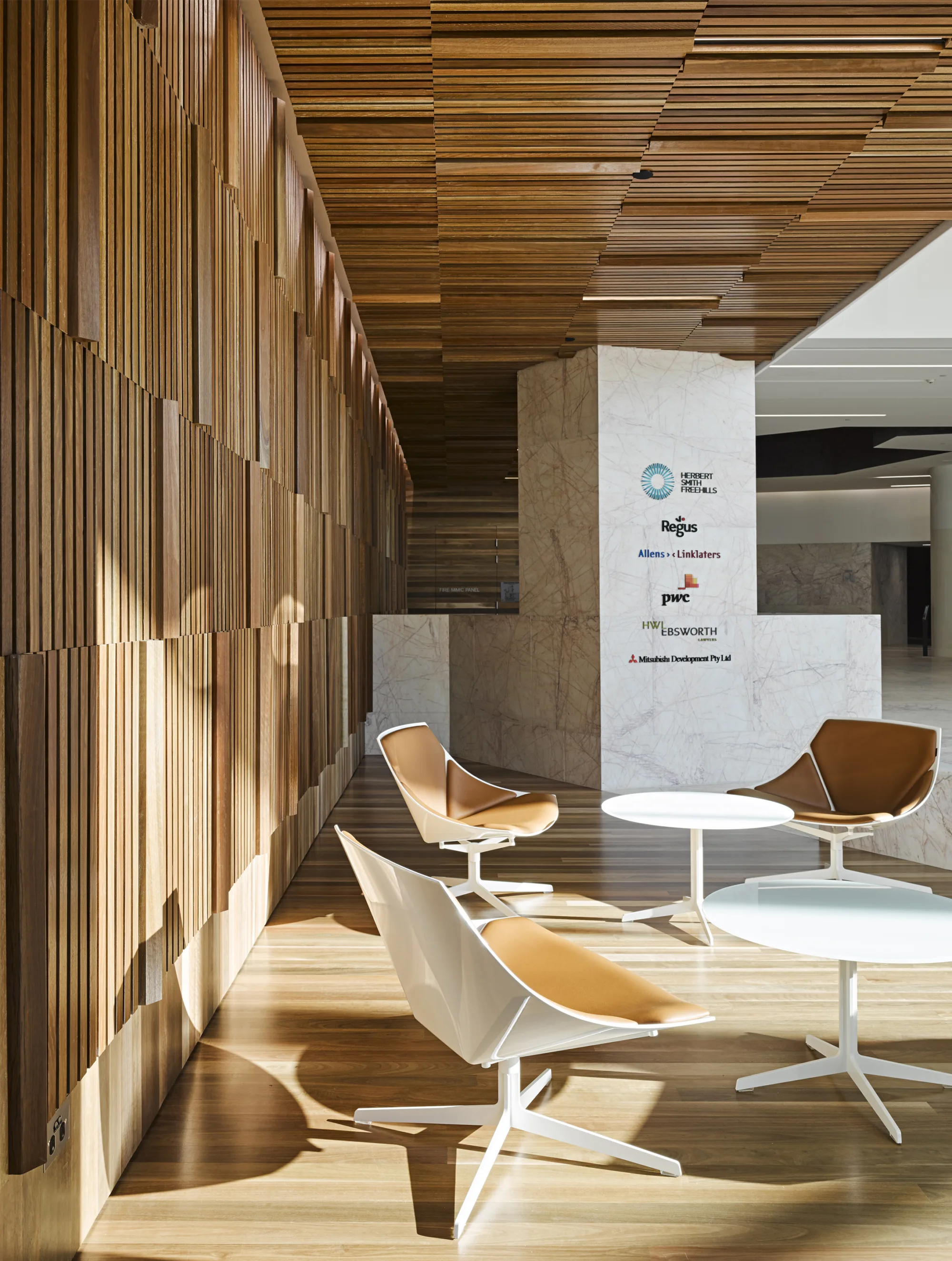 Interior meeting space with floor to ceiling wooden panelling featuring coordinated white and tan furniture.
