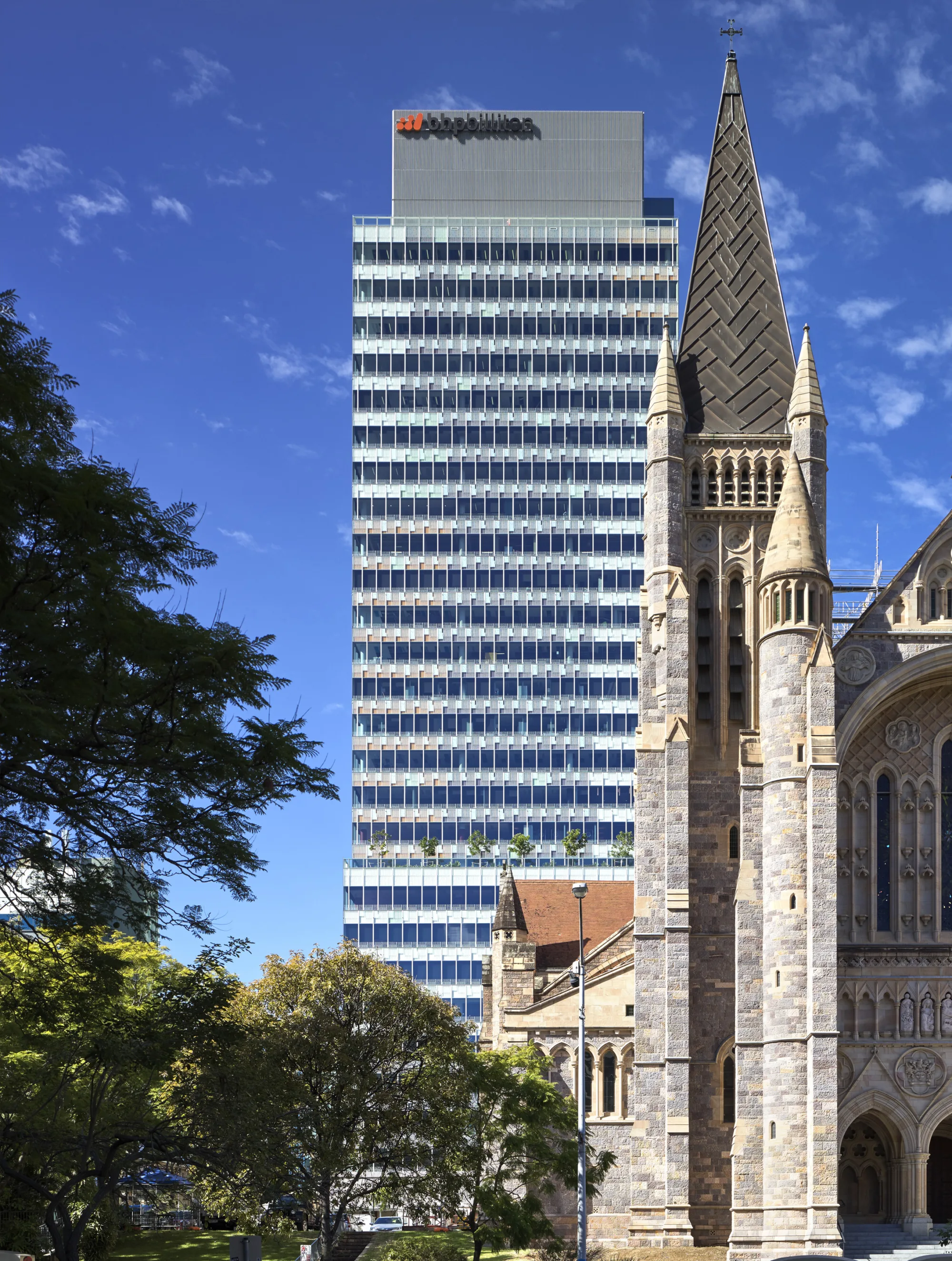 Street view of the building with a cathedral and greenery in the foreground.