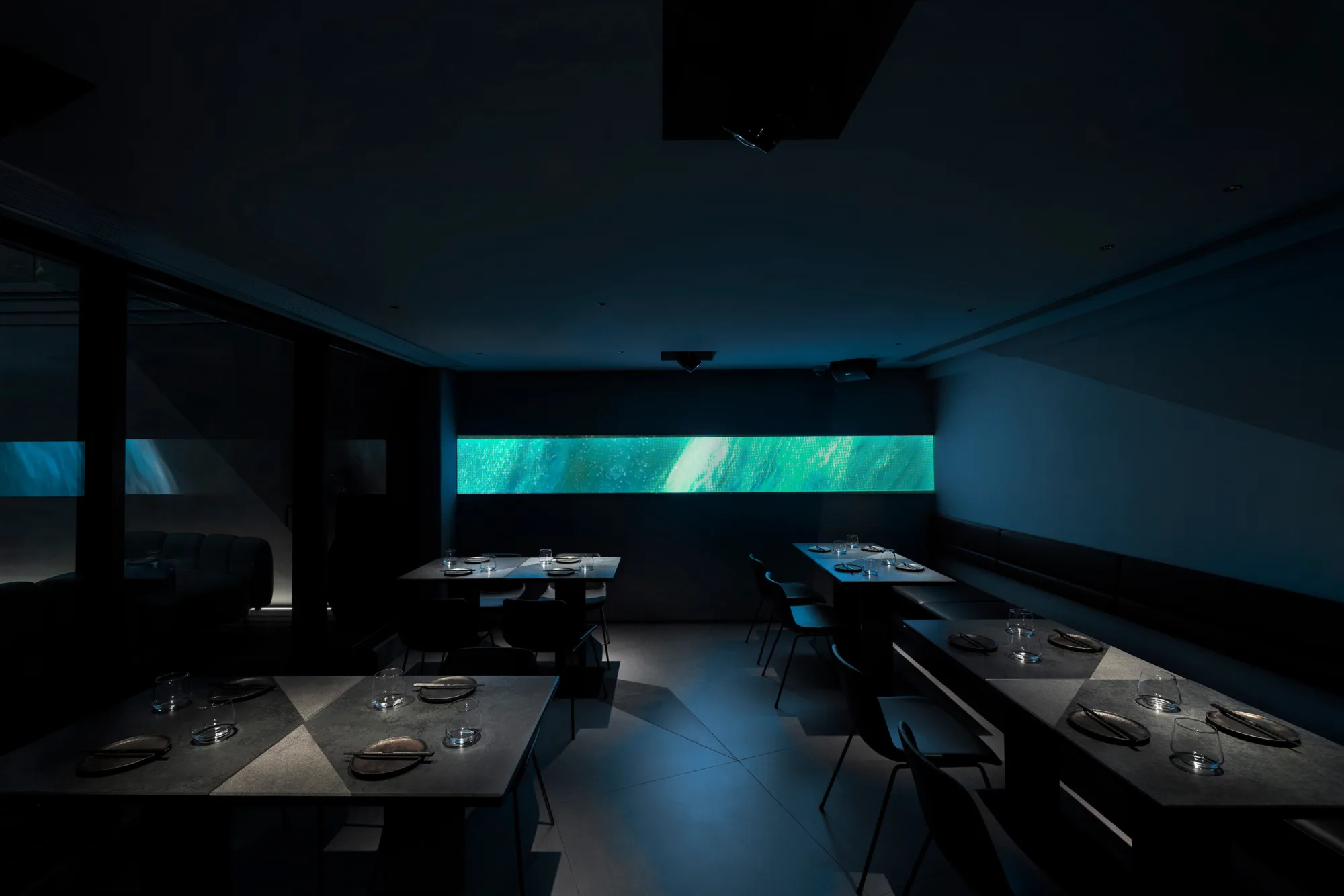 AOAO main dining area with spotlights on tables with illuminated green light at the backdrop.