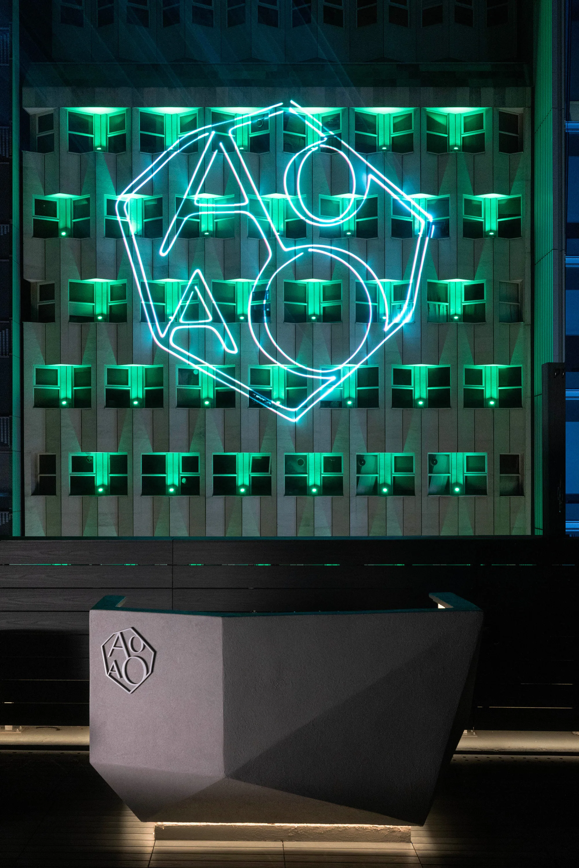 AOAO logo projection on the exterior of a building in green colour lighting.