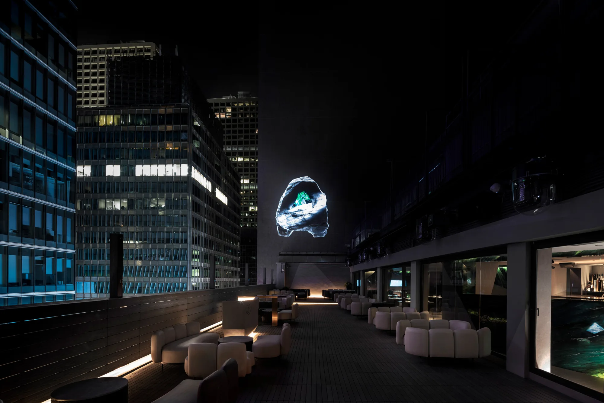 Outdoor dining area with a projection of AOAO graphic nestled with green colour light rays.