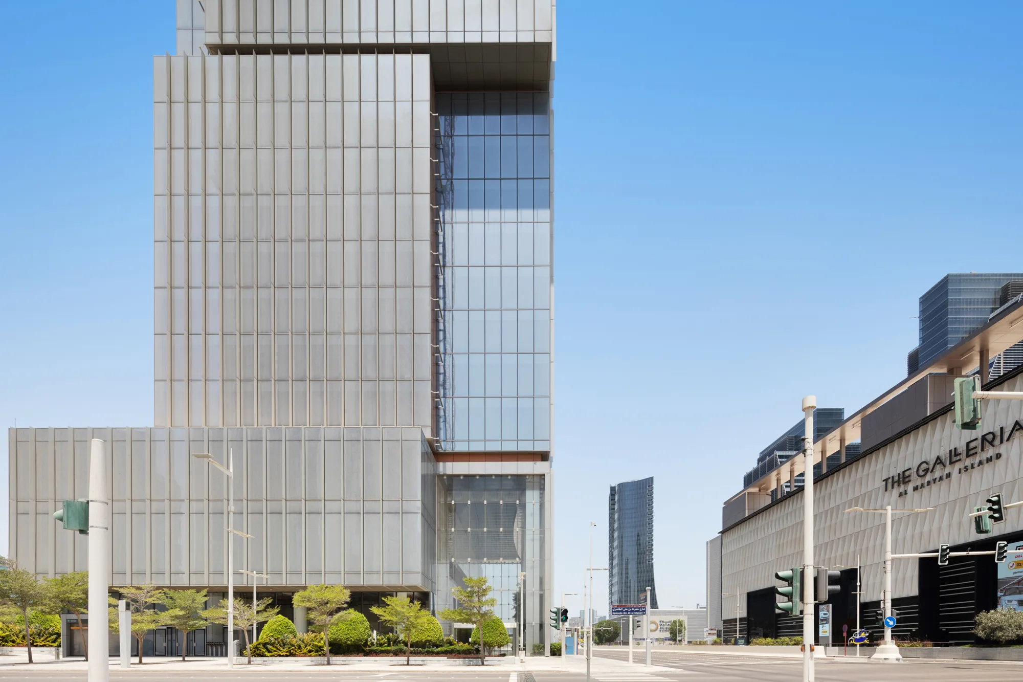 Wide view of a tall glass building across the street; adjacent to other structures including The Galleria mall.