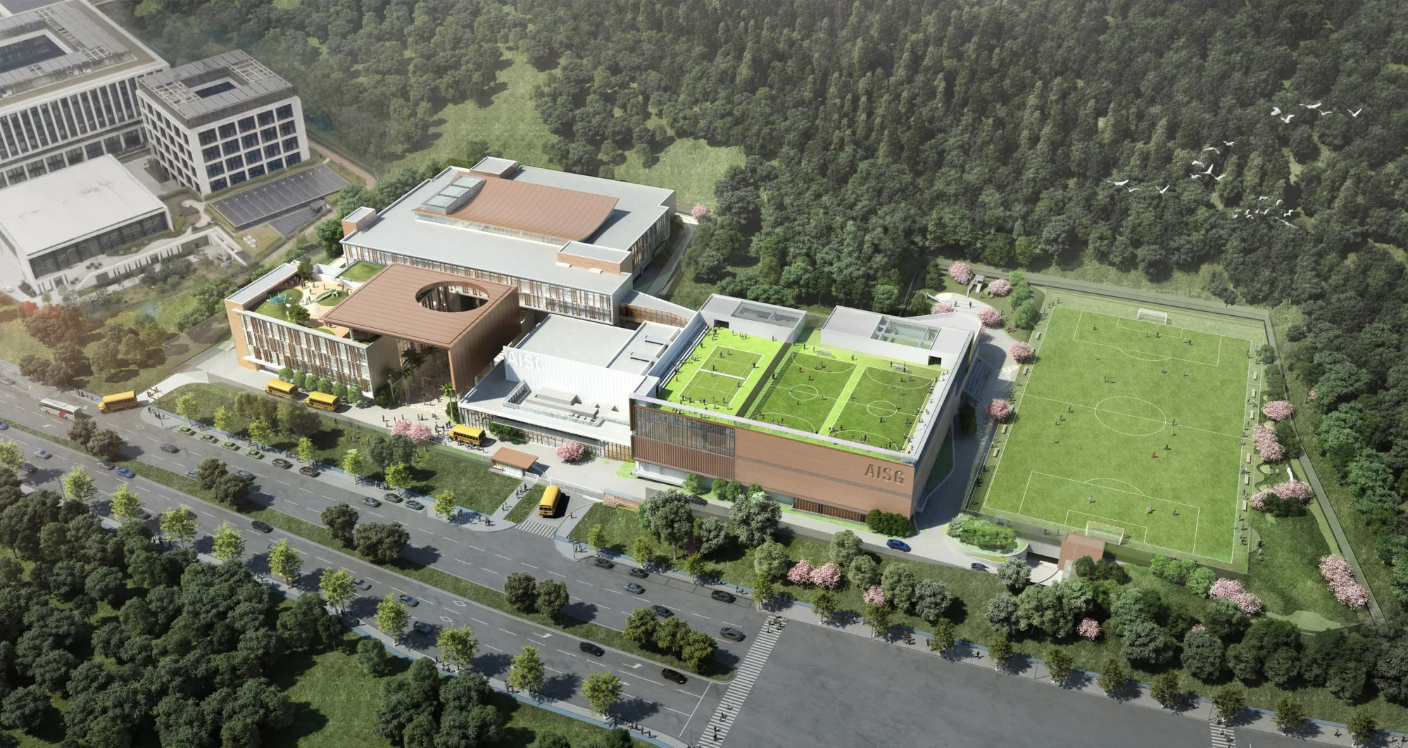 Overview shot of the whole campus. Main buildings, three sports fields, a tennis court, and a rooftop play space can be observed.