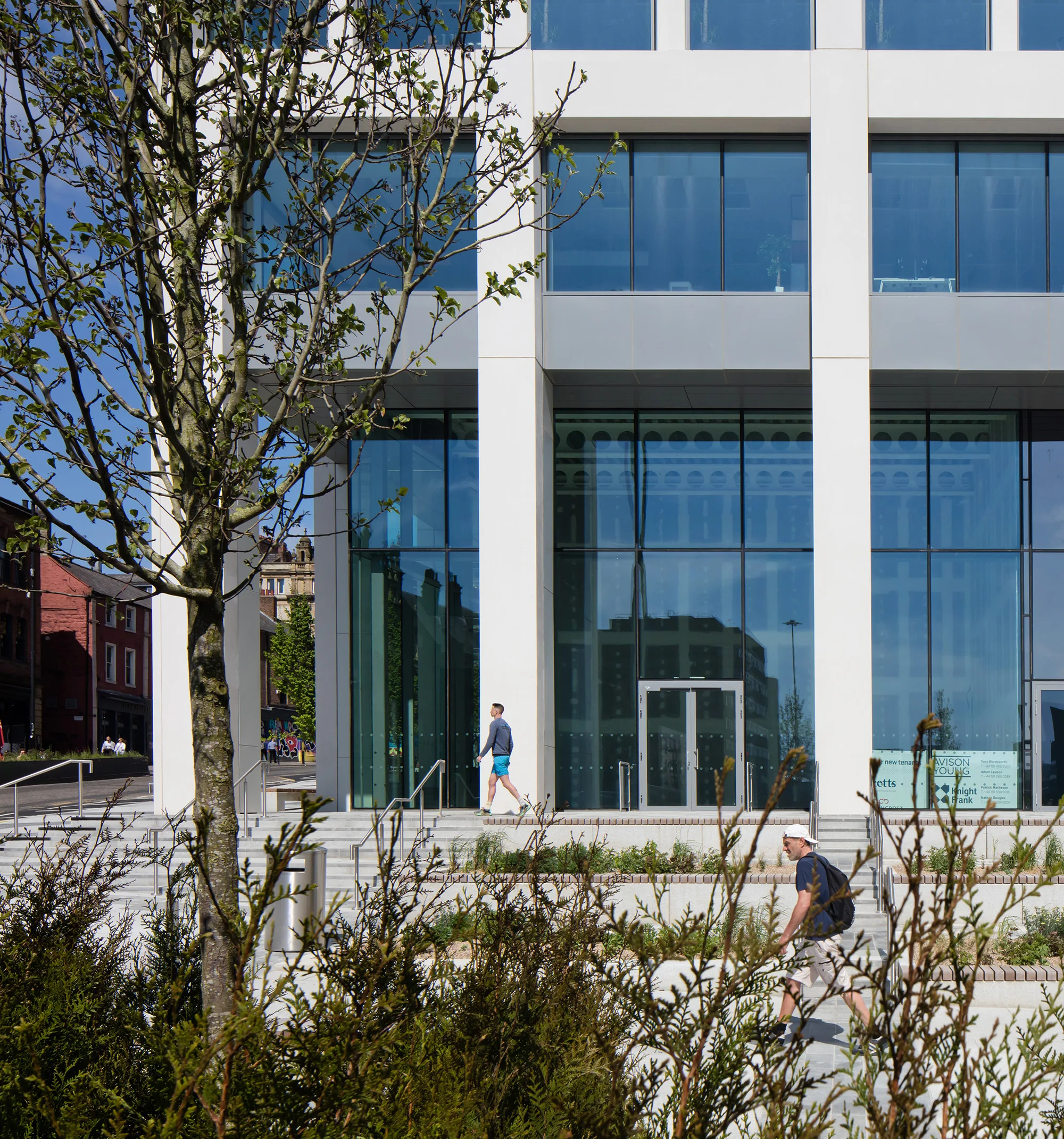 Building entrance with a glass and concrete façade with planting in front