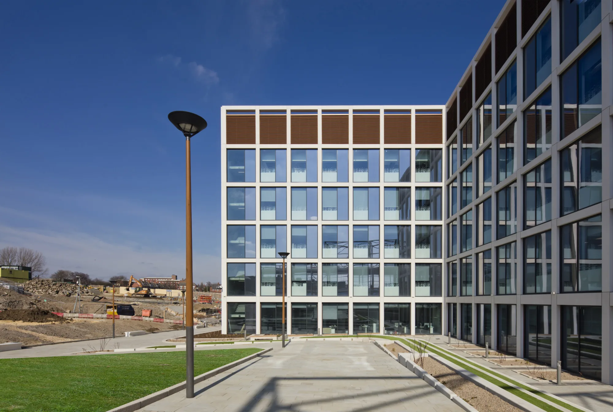 Exterior of a regular white walled building, a front-on view, next to a lamppost, against a blue sky