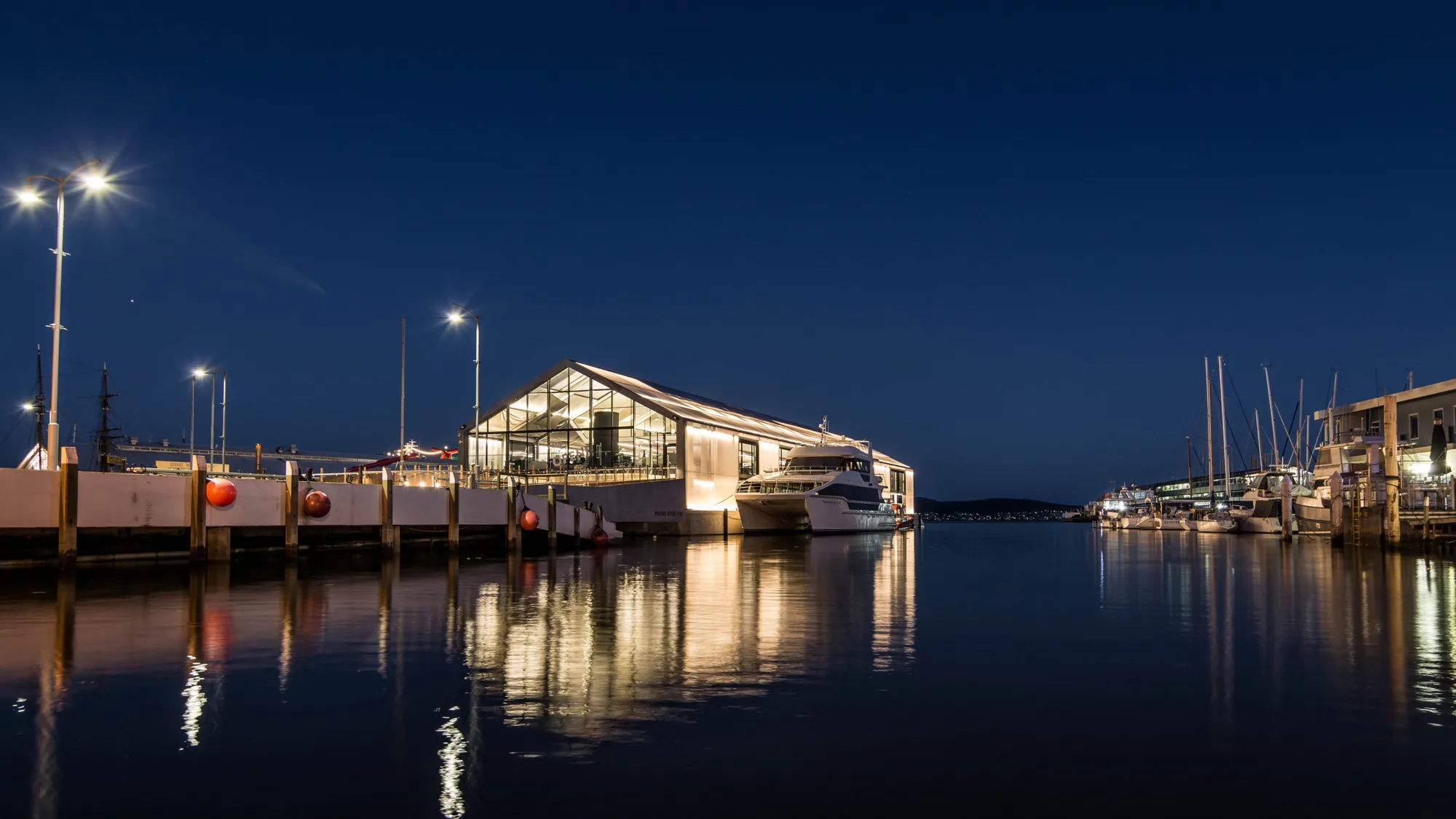 Brook Street Pier at dusk with floating terminal illuminated with boat docked