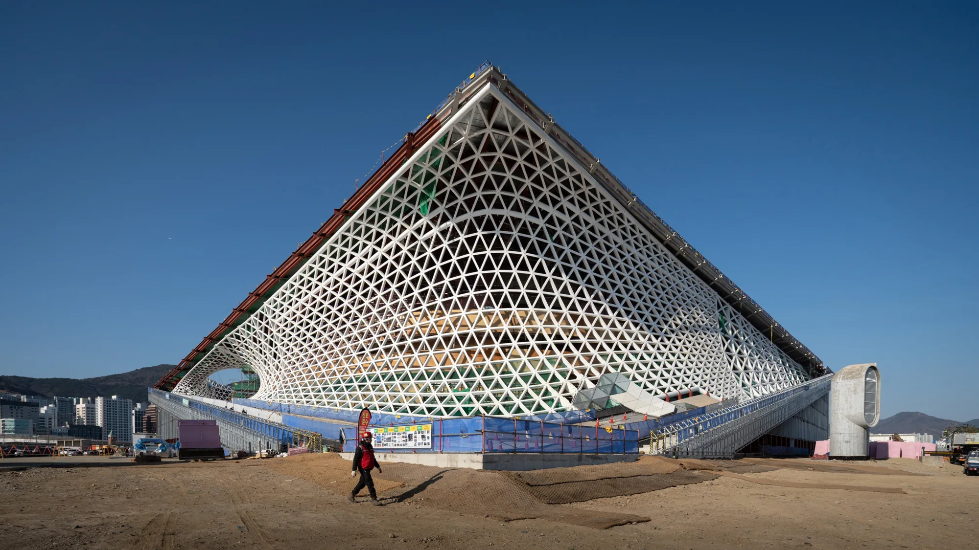 Construction progress photo of the Busan Opera House, highlighting the sharp triangular profile