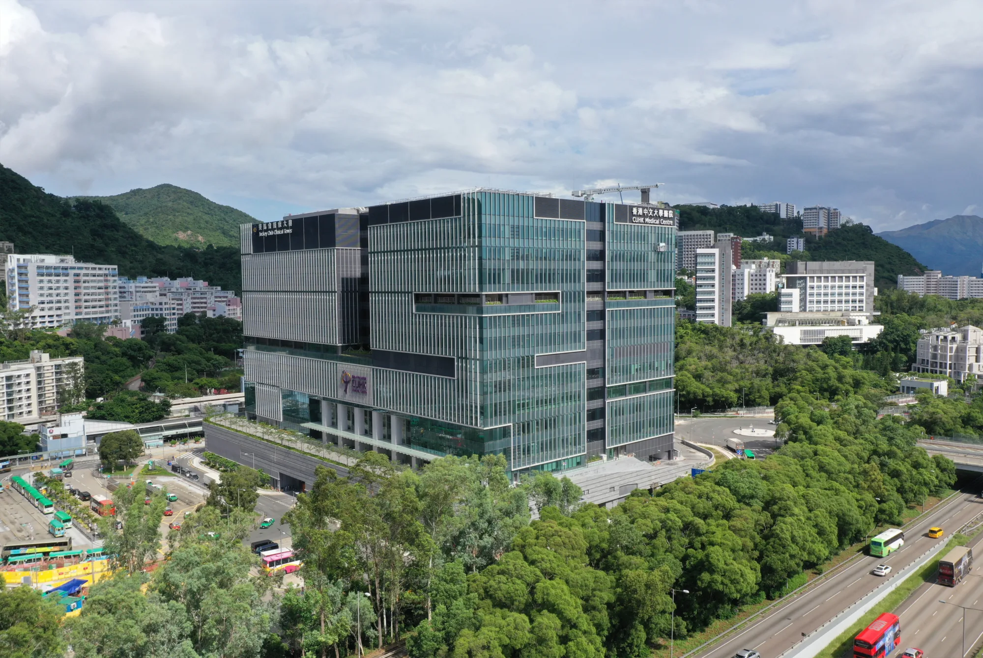 Whole building view showing the centre surrounded by trees, other buildings and mountains in the background