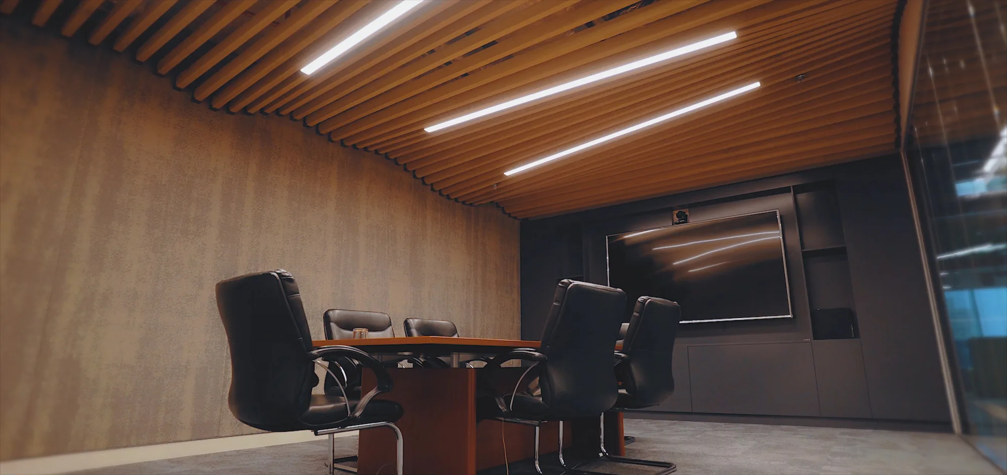 Cundall Dubai WELL office meeting room with a long table, black leather seats and a large tv