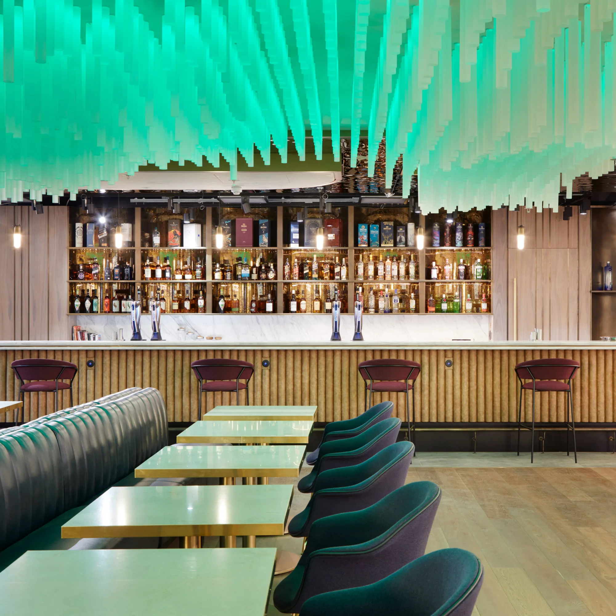 Seating area with the bar in the background and a green ceiling light installation