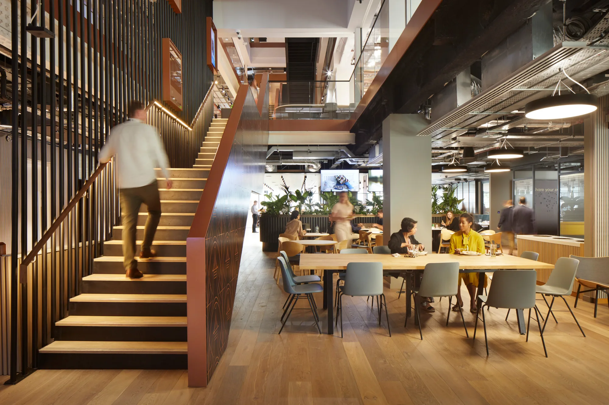 People seated in a breakout space with a person climbing the illuminated stairs