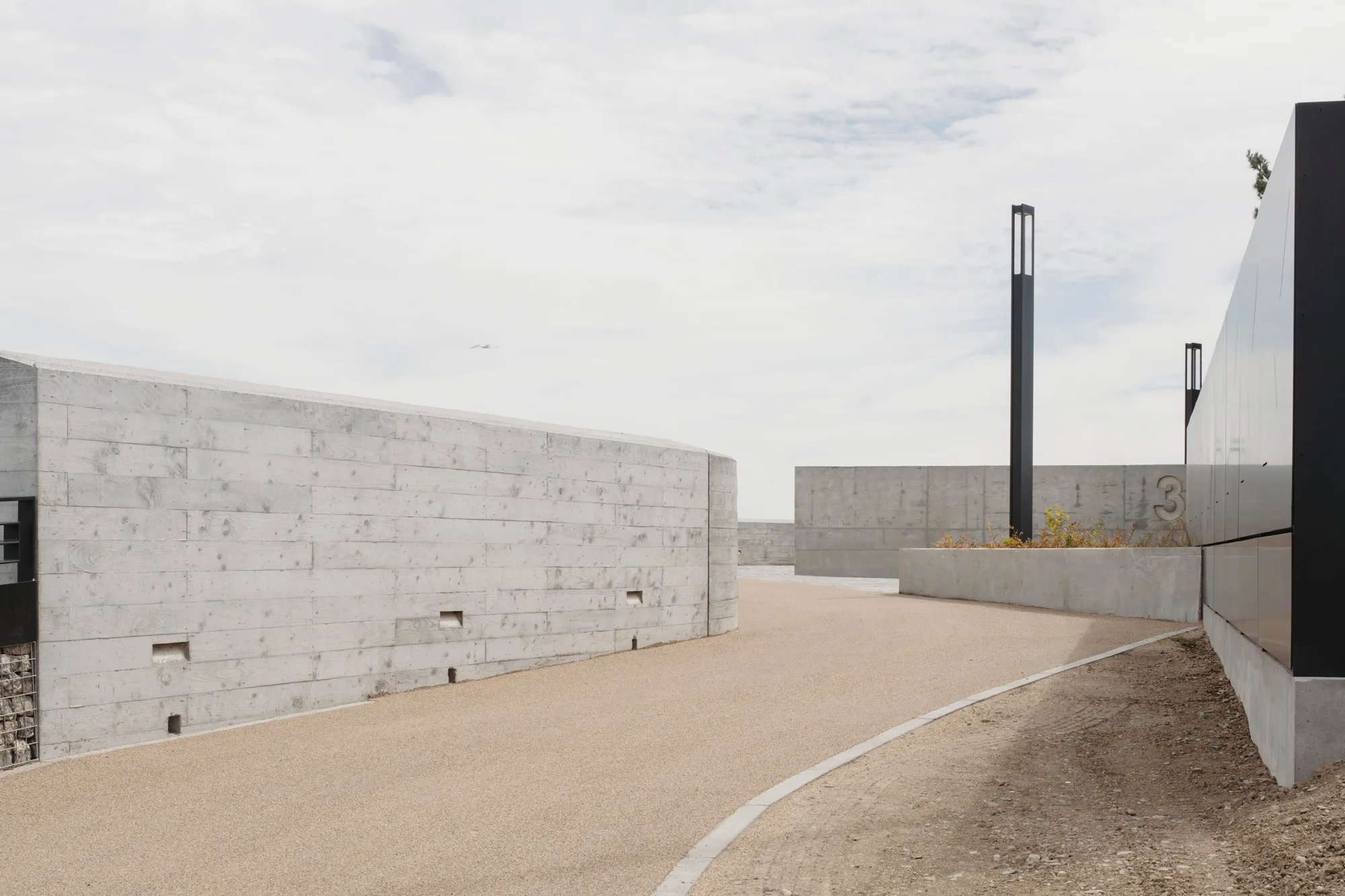Light concrete walkway surrounded by high walls