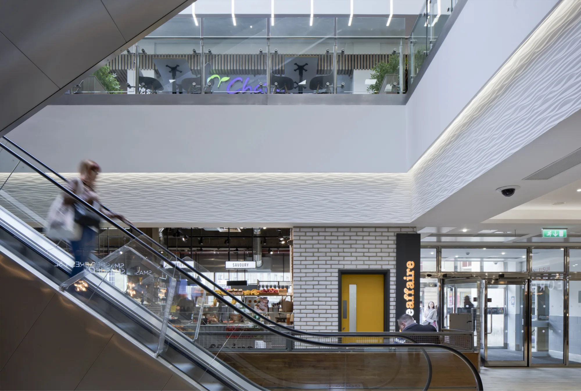 Interior of the shopping centre with an escalator carrying a person downstairs