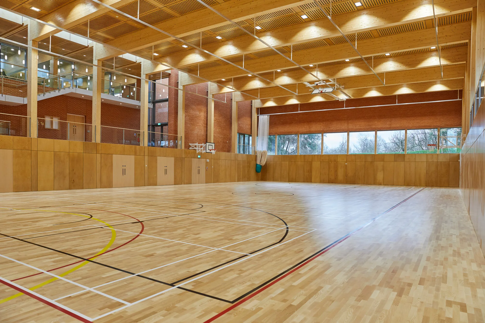 Inside a sports hall with basketball nets and a viewing platform overlooking the space.