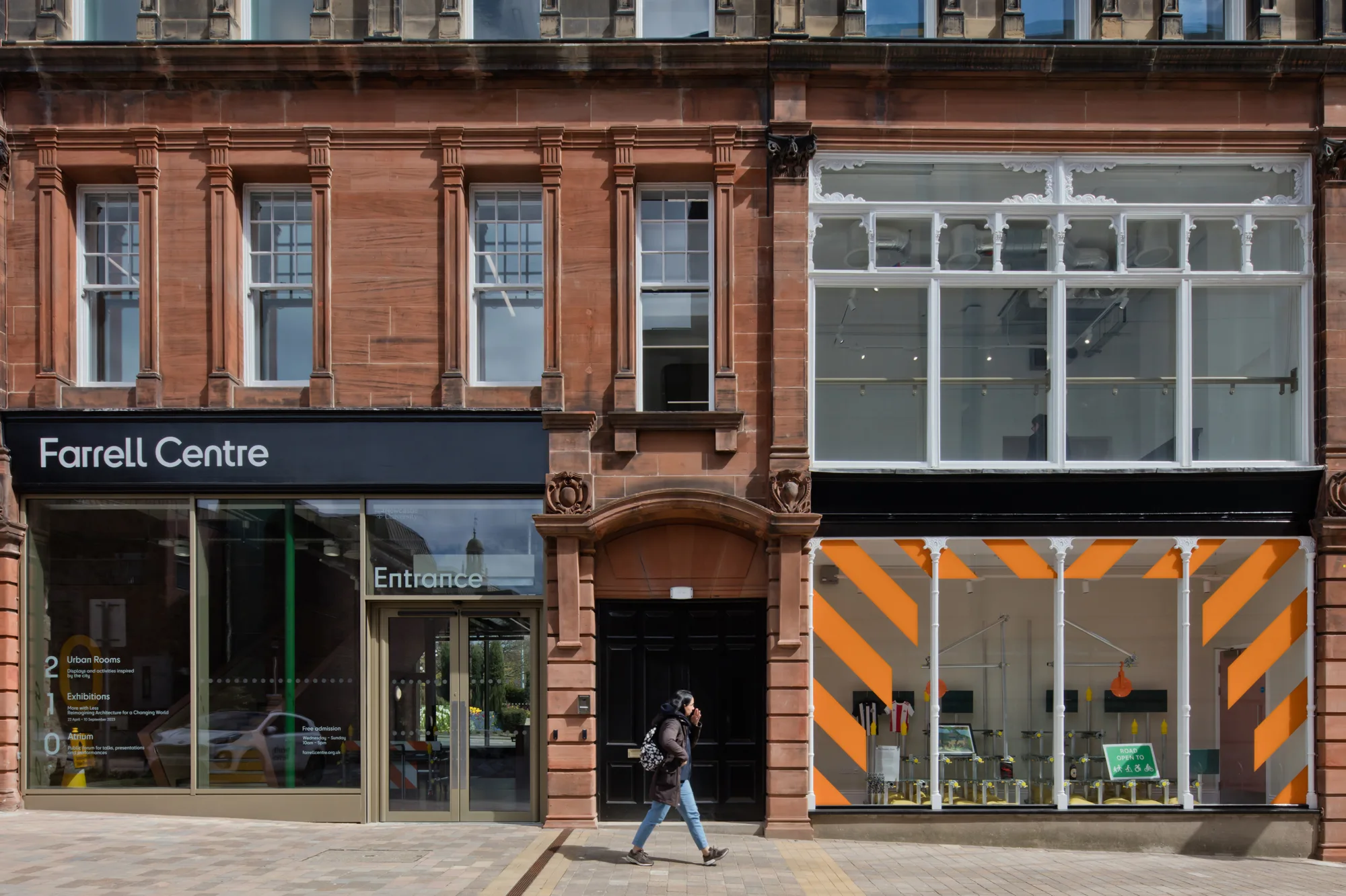 Person walking in front of buildin Farrel Centre shopfront sign clearly visable