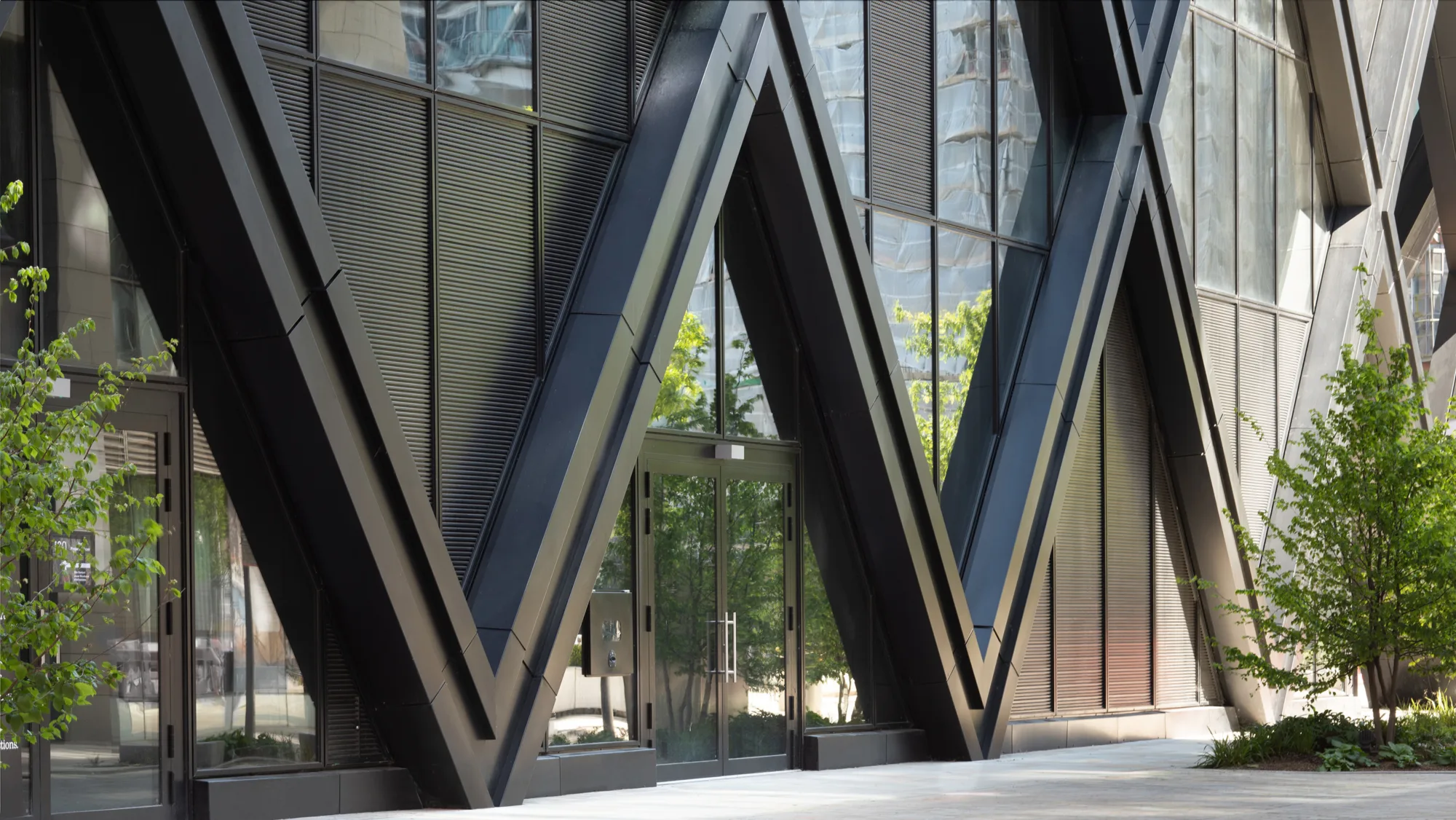 Exterior of a building featuring a thick steel wall with large glass panels, creating a modern and industrial look