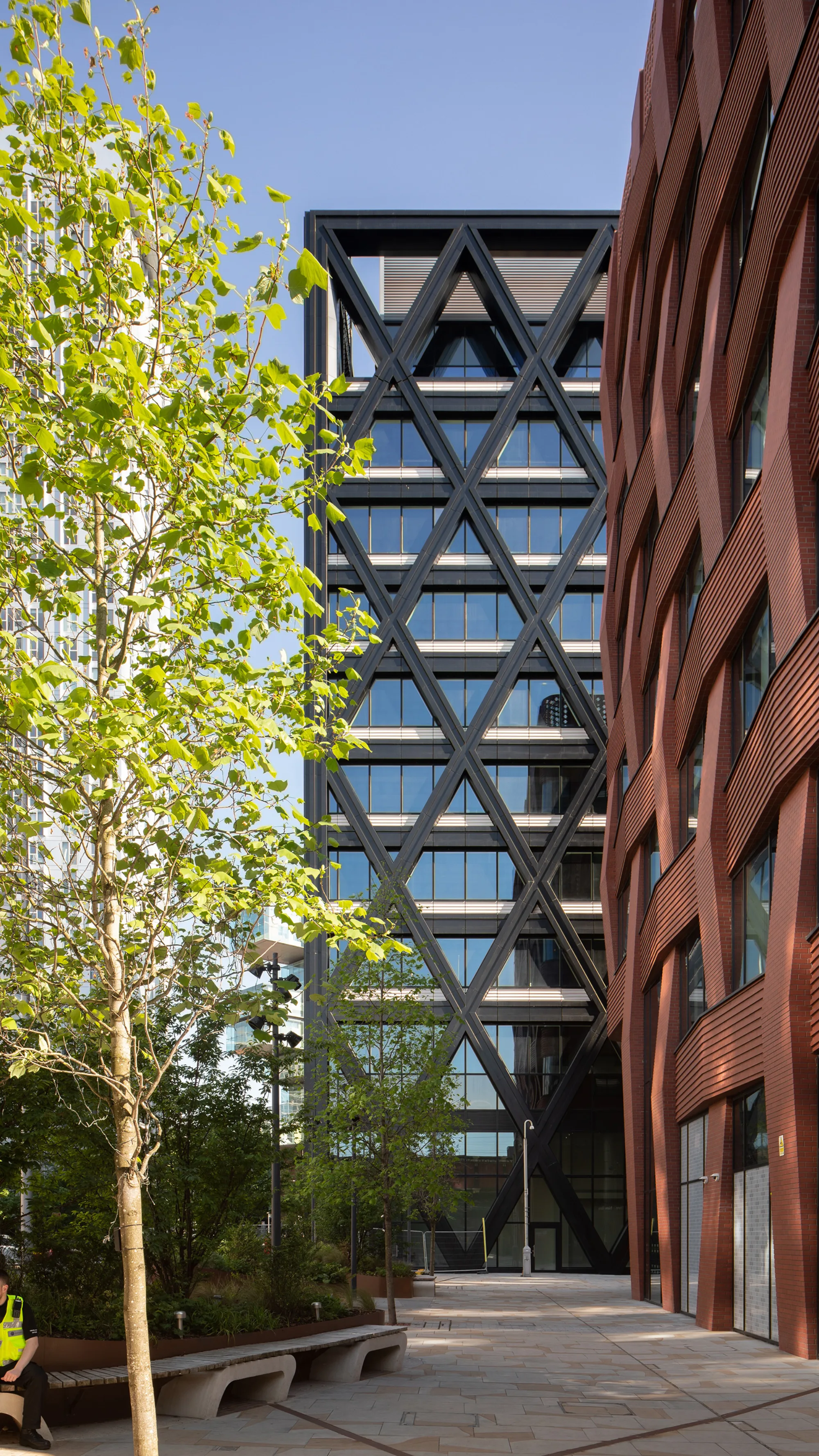 Exterior of a building with a landscaped area and wooden walls adjacent to a glass structure, combining natural and modern design elements