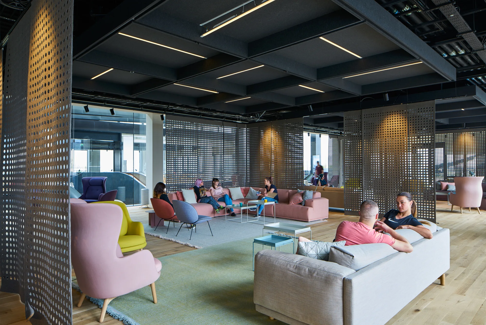 Open plan area with comfortable seating in soft colours, two groups of people having a conversation