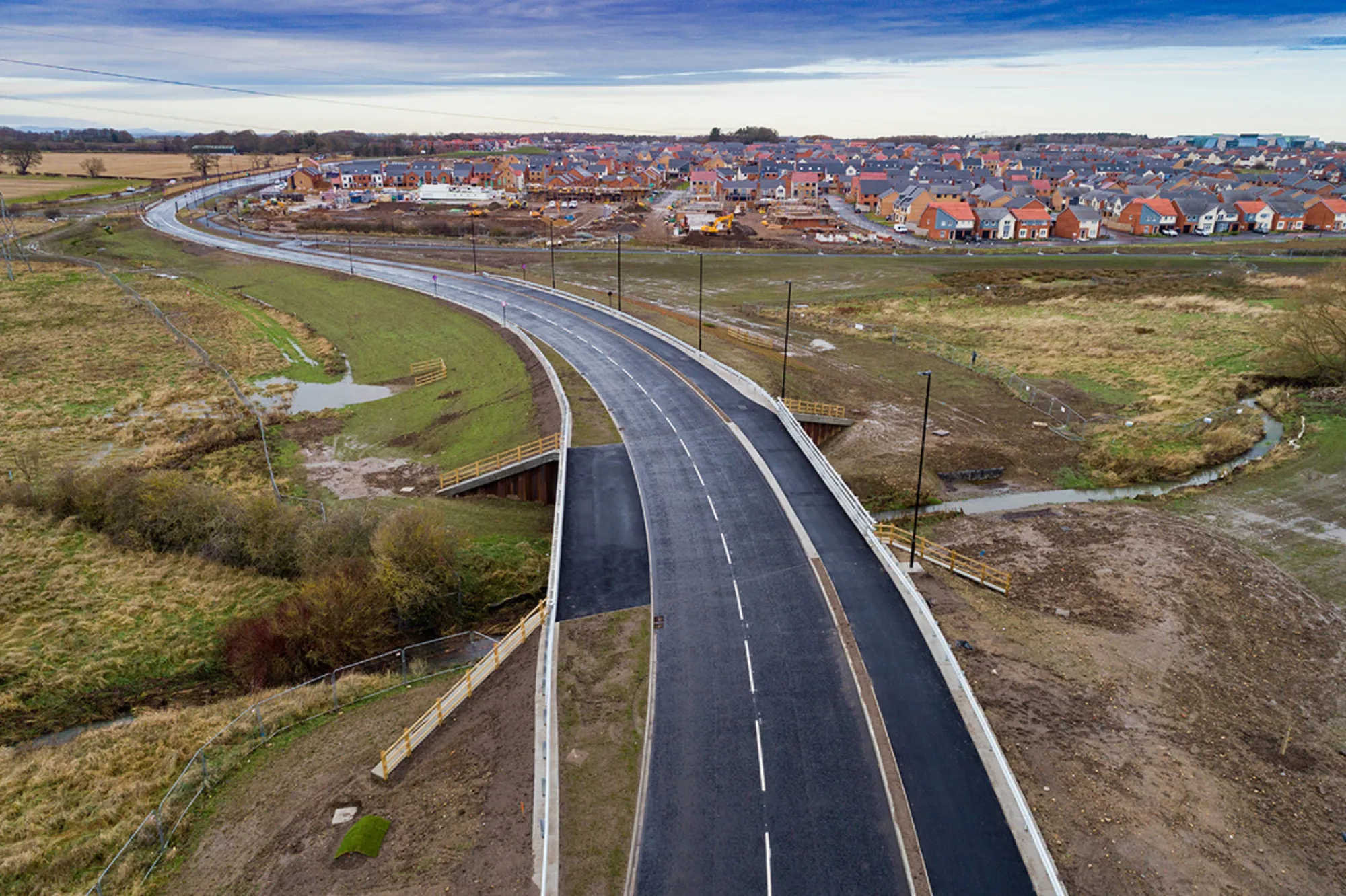 New tarmac road leading into house estate on a grey winter day