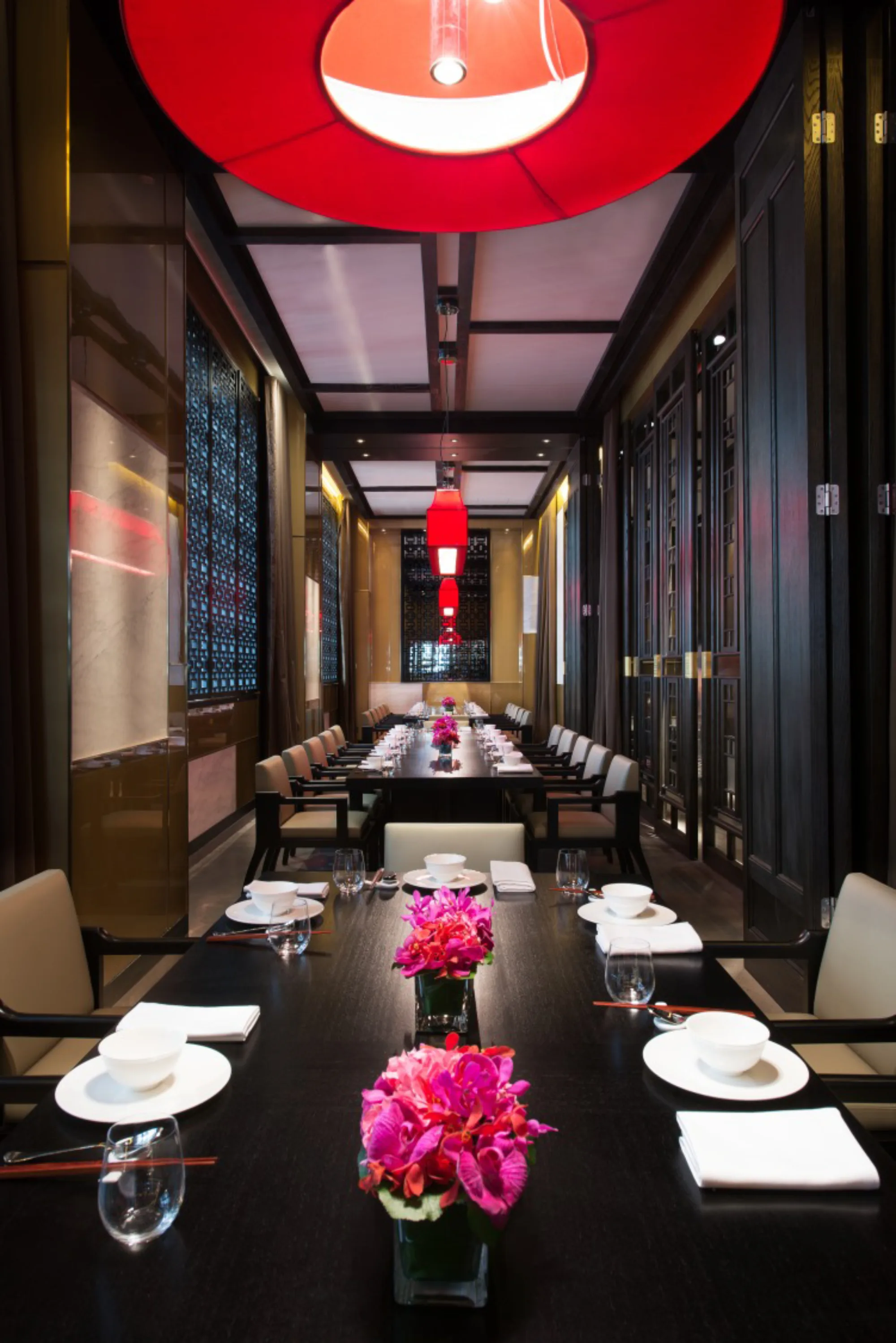 Private dining room with long dining tables lined with chairs and lantern-inspired lights