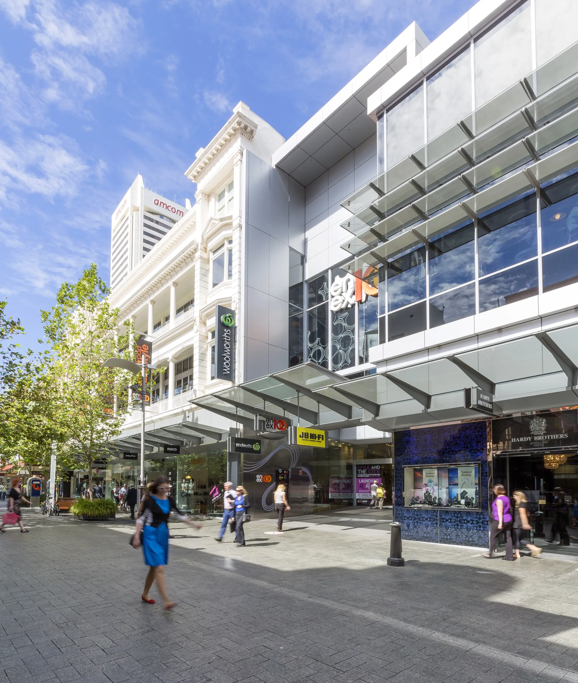 A busy street scape in a large shopping precinct with people walking by.
