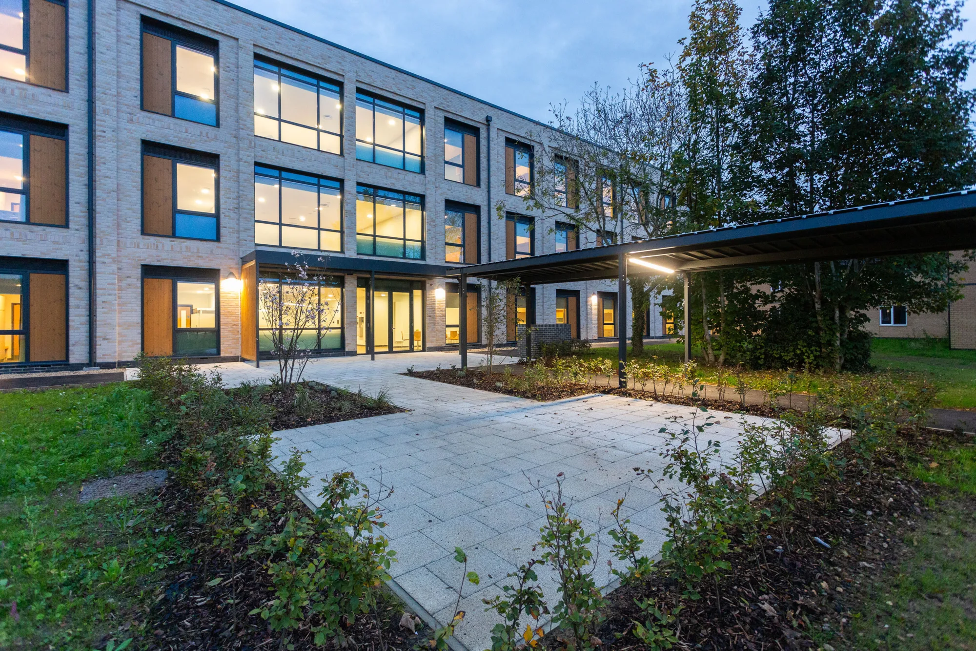 Exterior of Imjin barracks viewed through the garden at low light with warm yellow light inside the building