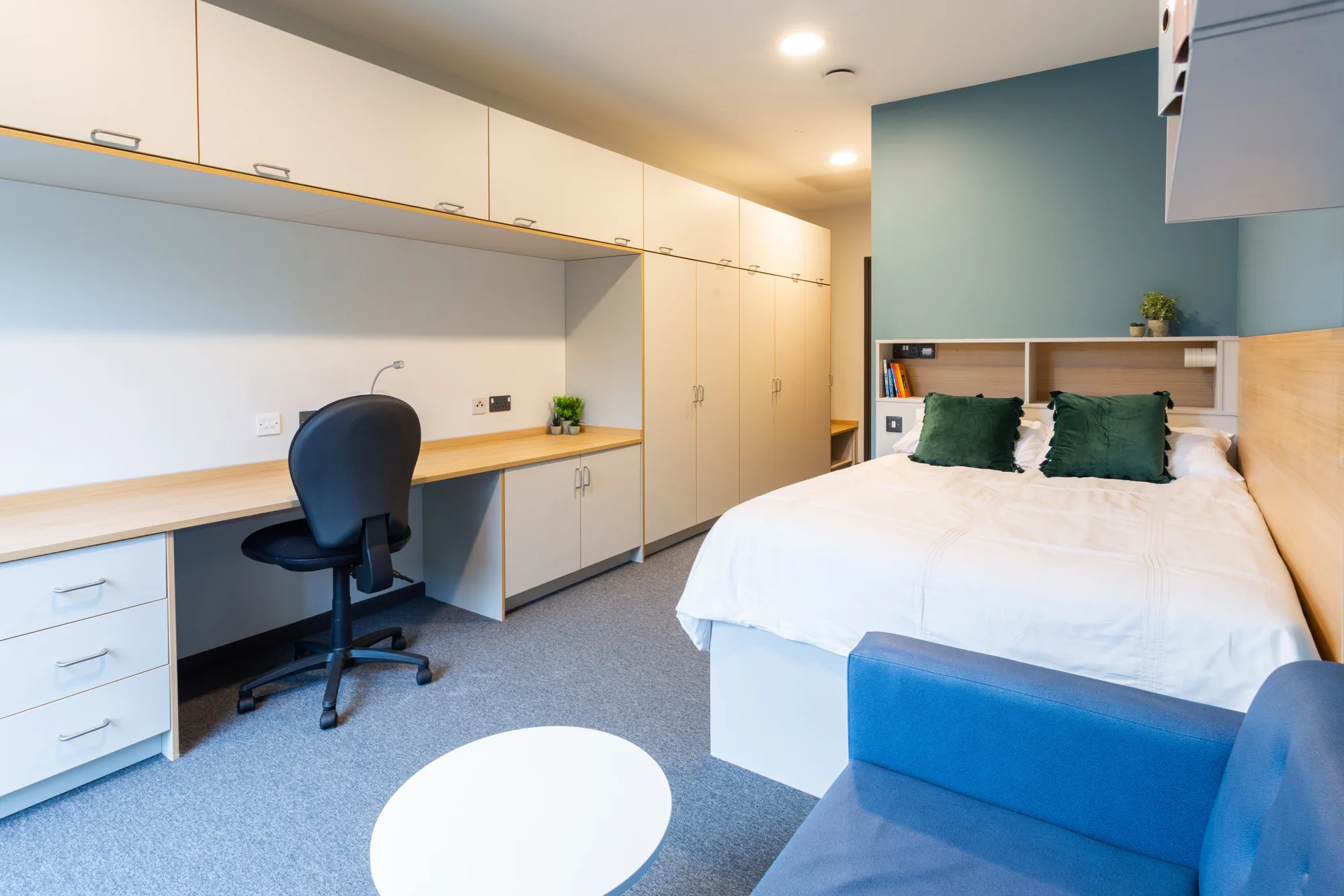 Double bed, armchair and coffee table and workstation and cupboards in the living quarters