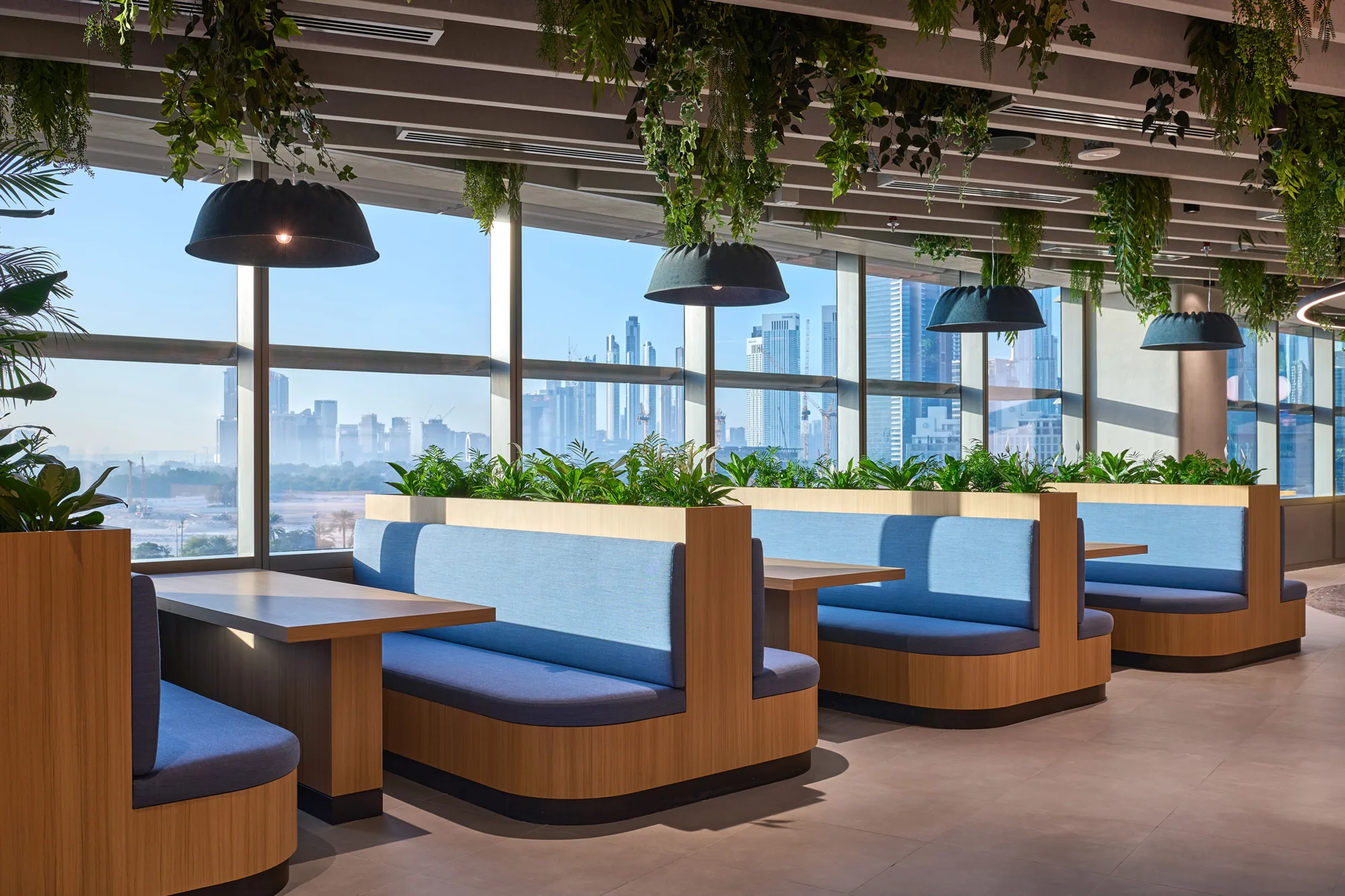 Informa office blue booths seating area with the Dubai skyline in the distance.