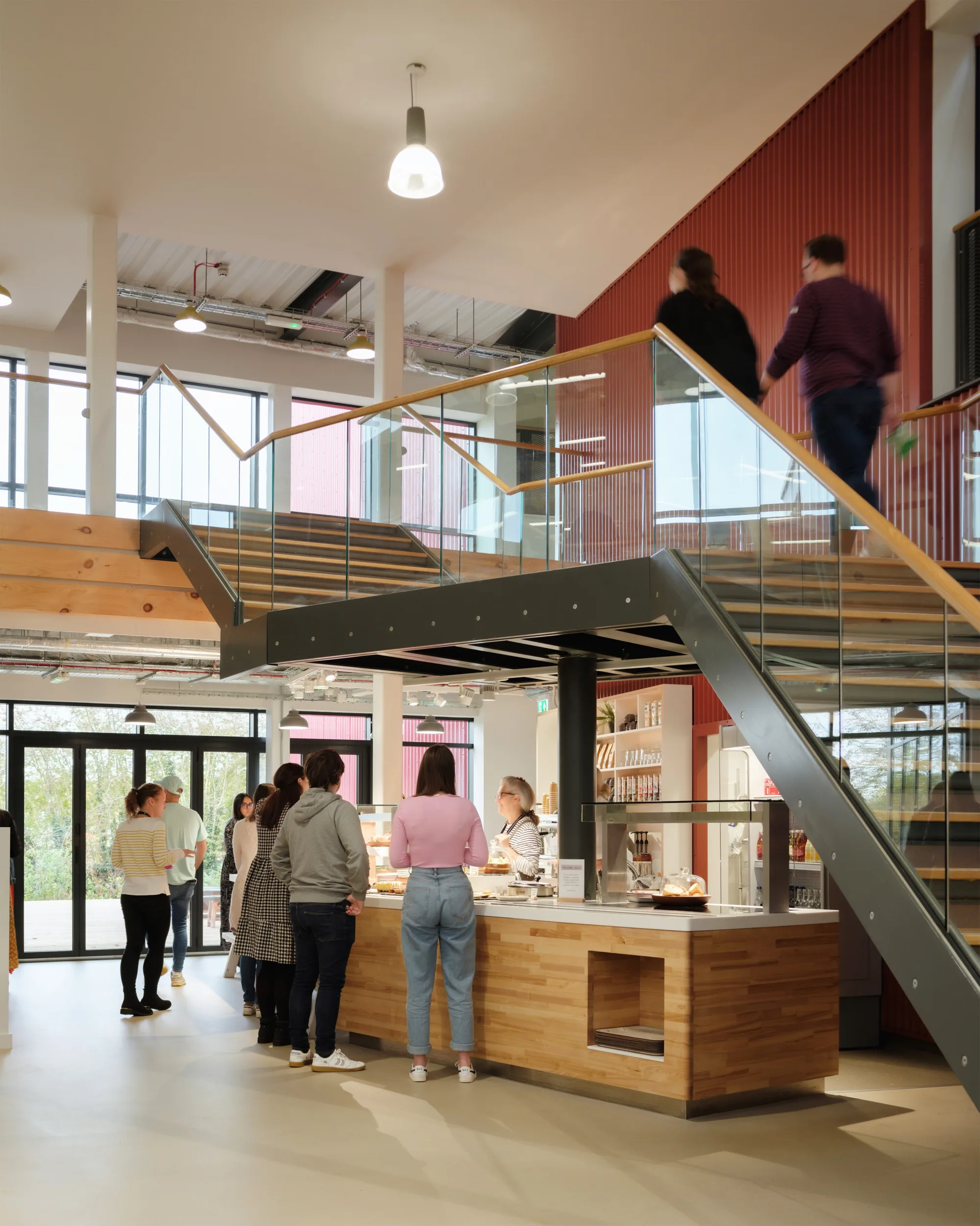 Glass stairway with a busy café bar underneath, with a queue of people
