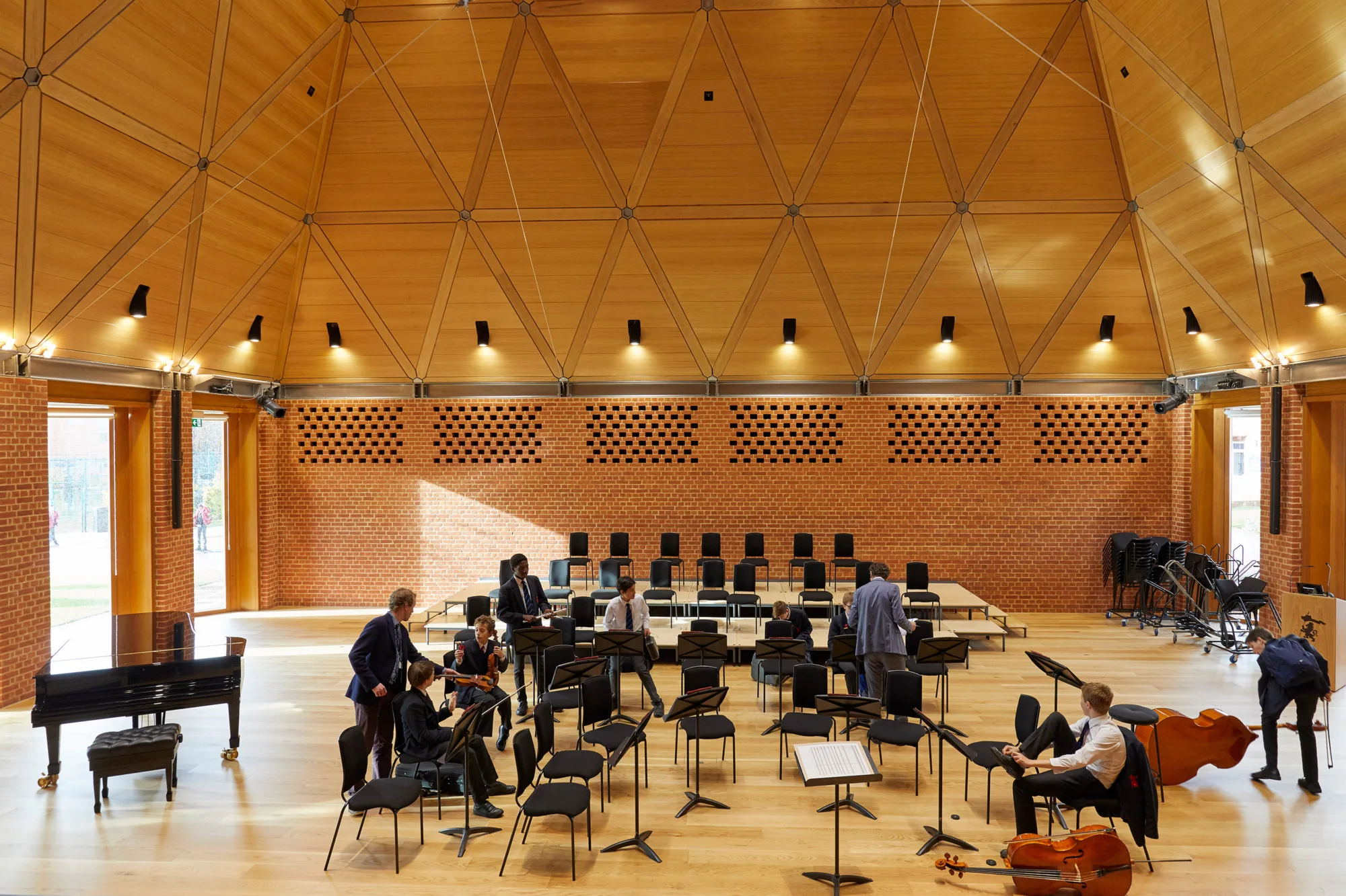 Students in the orchestra seated with instruments in the auditorium