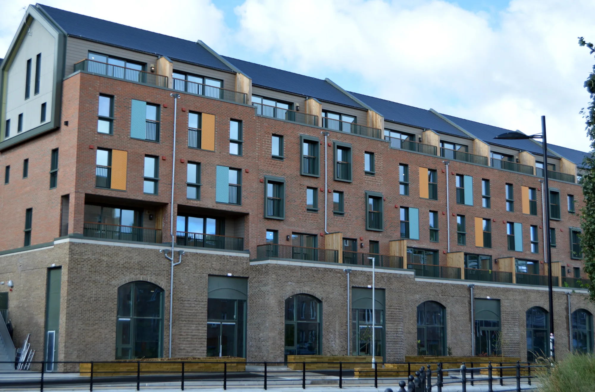 5 story apartments with lower brick walls and arch ways and dark grey roofs